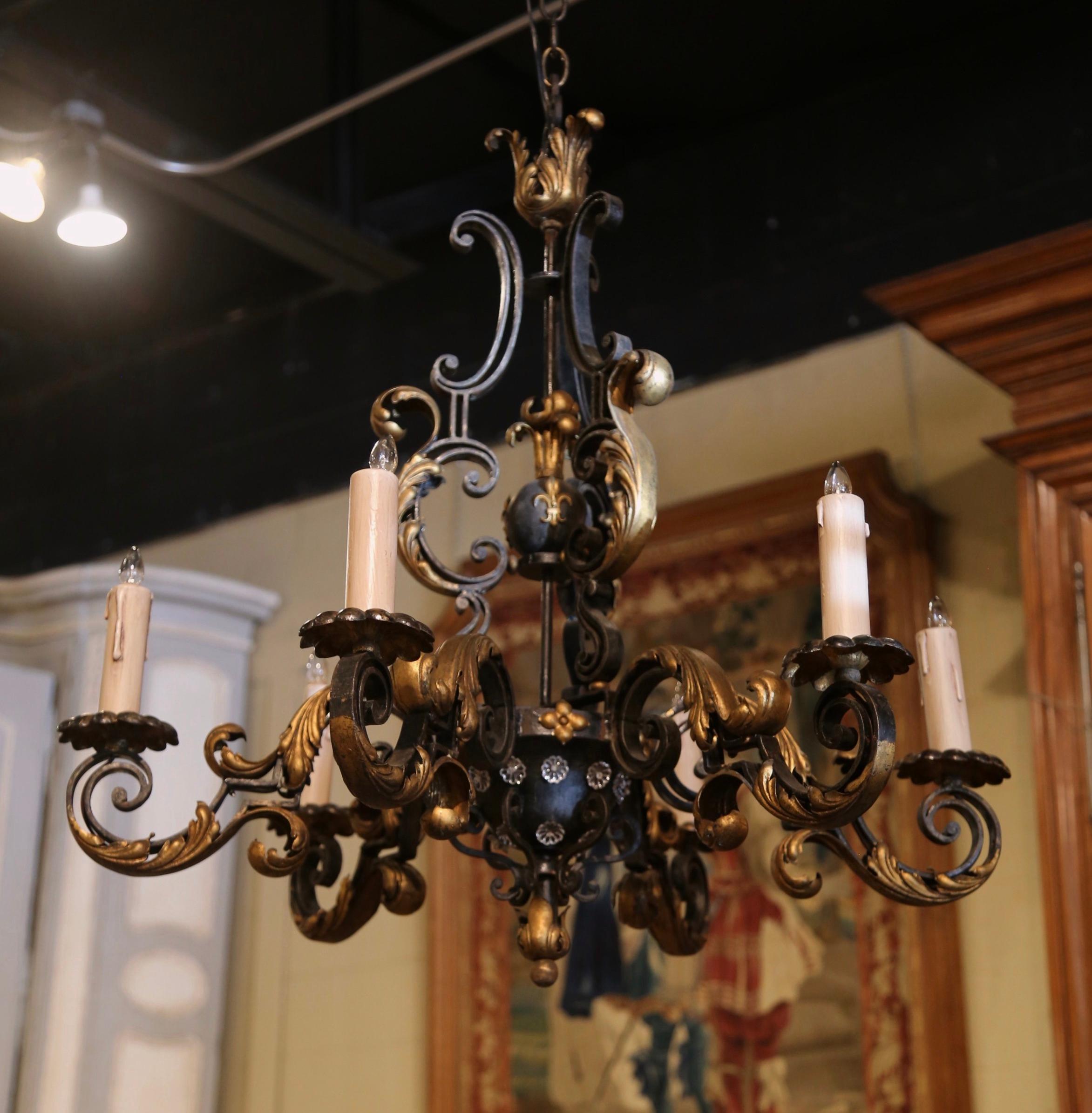 This elegant antique chandelier was created in France, circa 1920. Round in shape, and built of iron, the chandelier features a center triple stem decorated with Fleur de Lys motif in high relief. The fixture has six forged double scroll arms newly