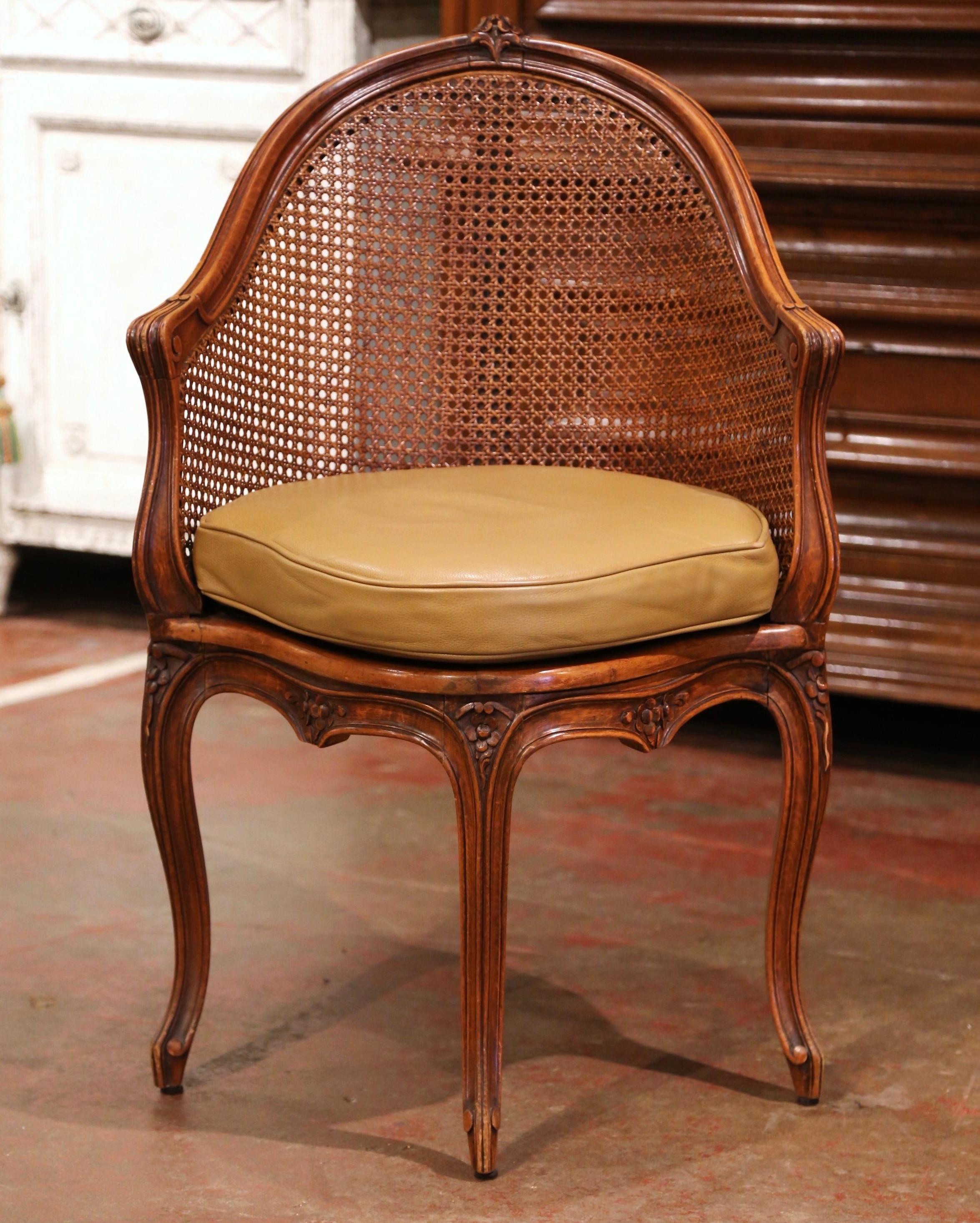 Decorate a study or office with this elegant antique desk armchair. Crafted in Provence, France, circa 1900, the corner chair has an arched cane back decorated at the top with floral motif. The traditional desk chair stands on four carved cabriole
