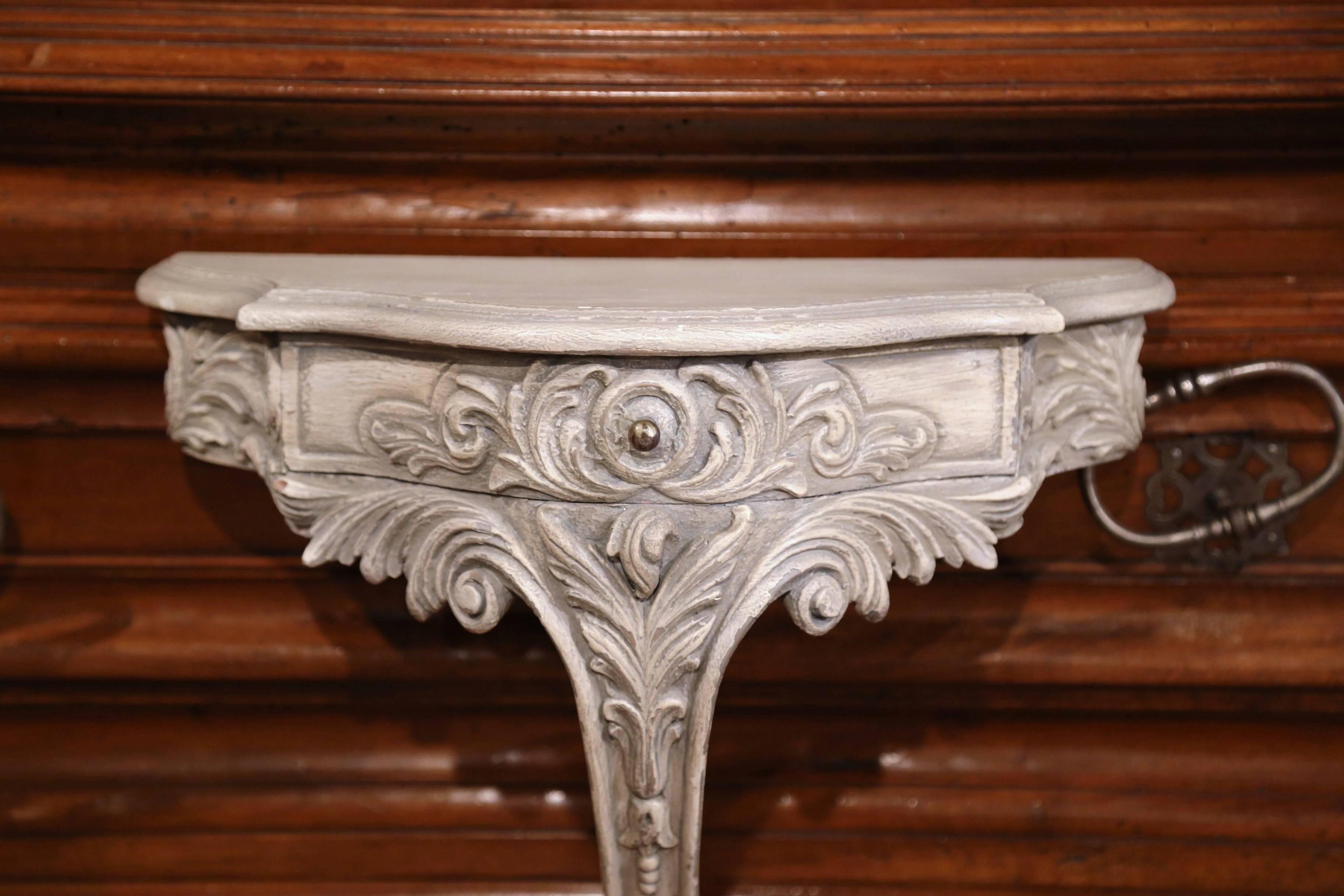 Place a vase or a bust on this elegant antique wall hanging bracket. Crafted in France, circa 1920, the bombe front console table features a center drawer with iron pull, shaped sides, and exquisite carving throughout including hand carved acanthus