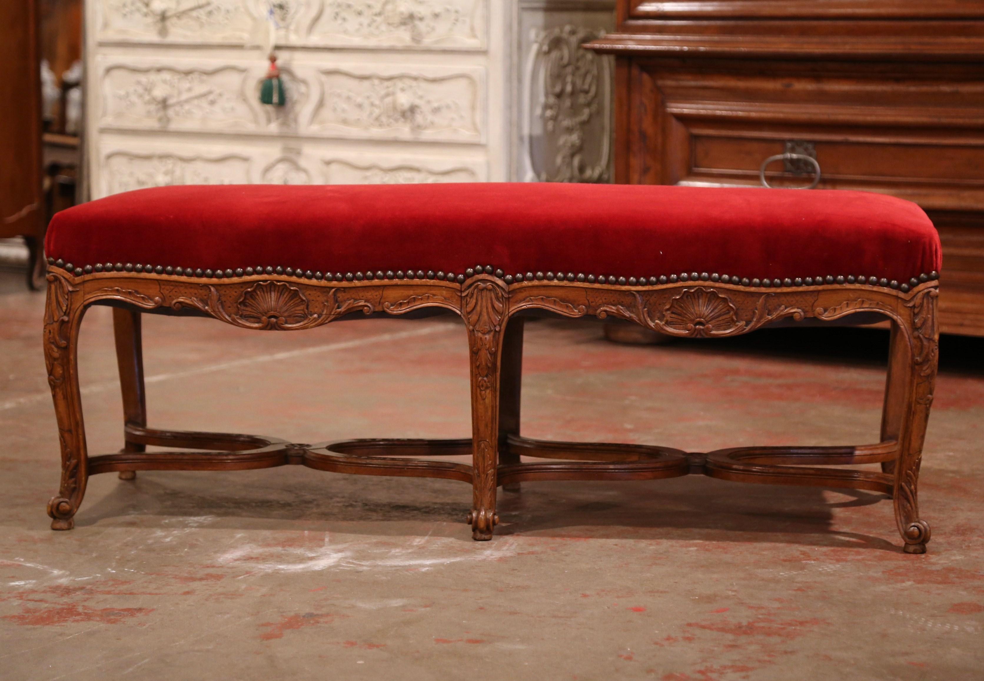 Crafted in Provence, France circa 1920, the fruit wood bench stands on six cabriole legs decorated with acanthus leaf motifs at the shoulder. The bench features a curved stretcher at the bottom decorated with carved leaves and flowers and
