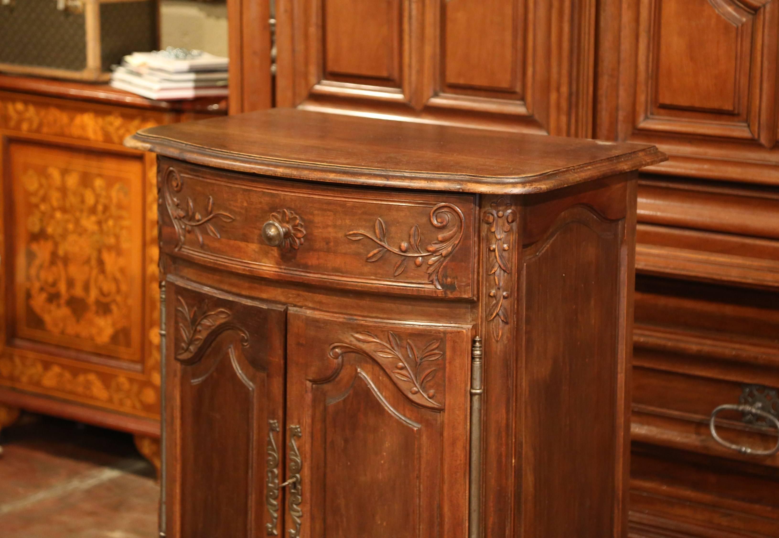 This antique fruit wood buffet was carved in southern France, circa 1920; the confiturier (French for jelly cabinet), sits on scroll feet and features a bowed front facade with carved centre drawer and two doors with inside shelving. The scalloped