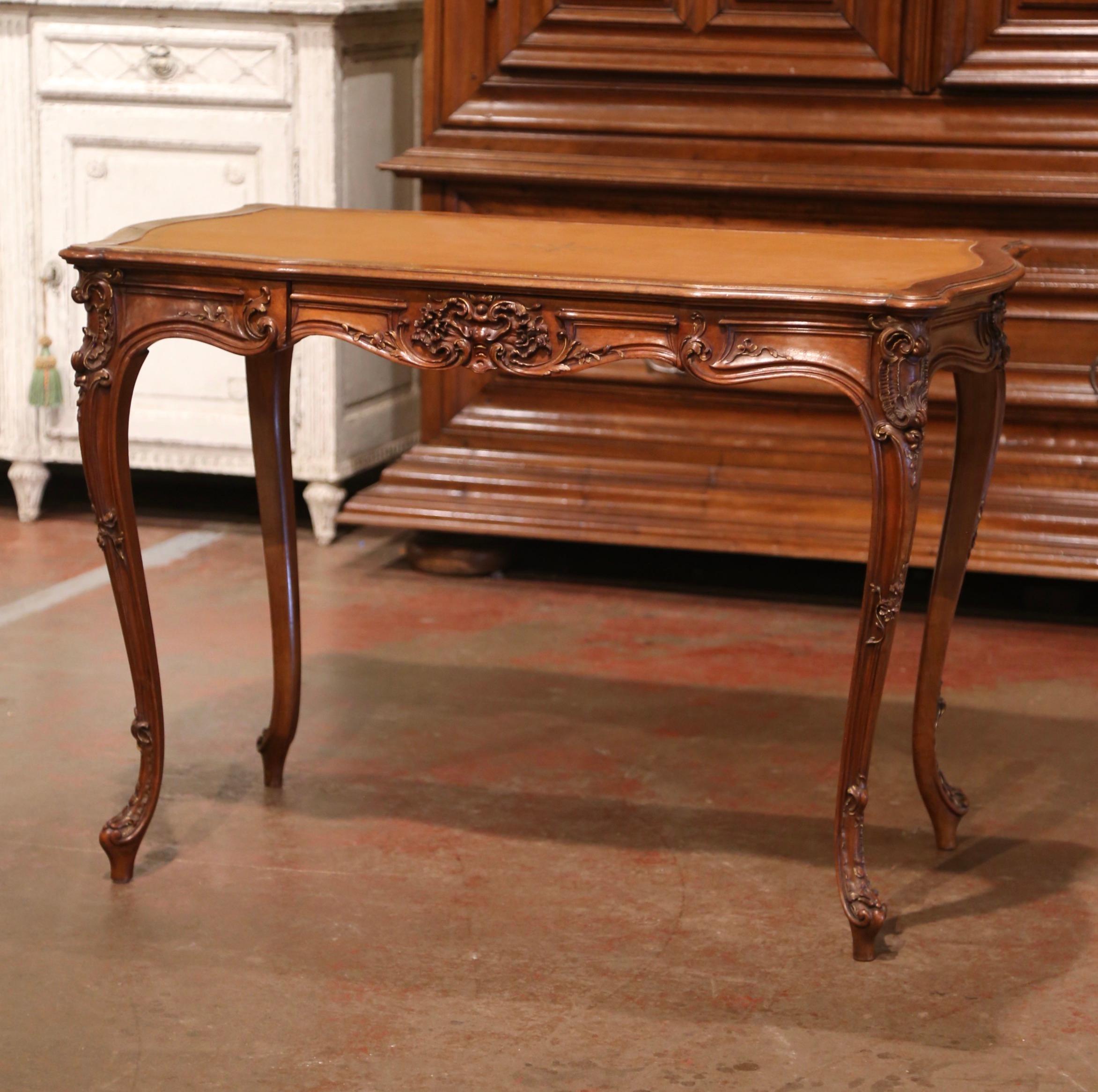 This elegant antique table was crafted in France, circa 1920. Rectangular in shape with serpentine edges and bombe sides, the lady's desk stands on cabriole legs decorated with acanthus leaf motifs at the shoulder, ending with escargot feet. The