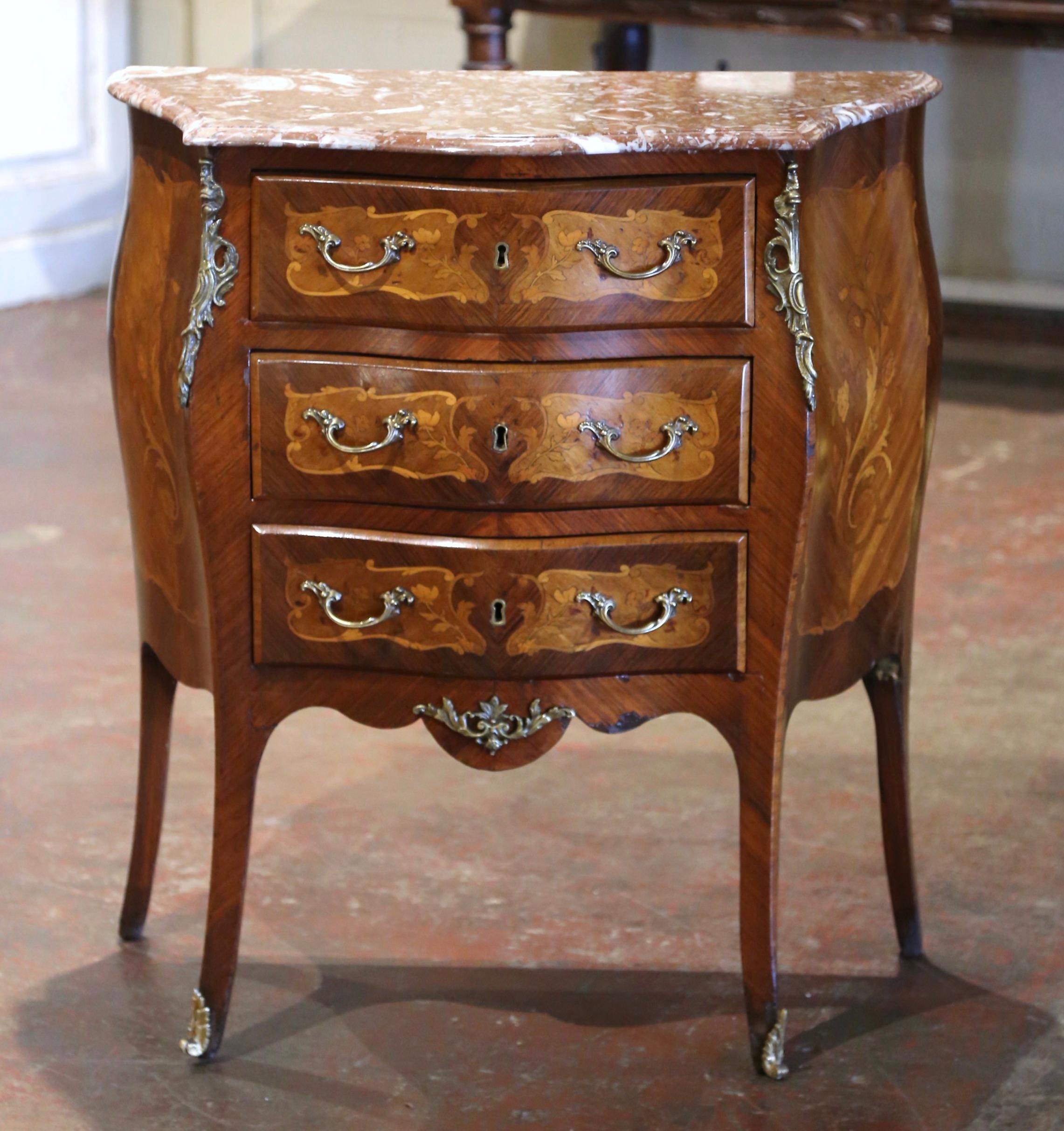 Fabriquée en France vers 1920, la commode vintage repose sur des pieds en cabriole, au-dessus d'un tablier festonné décoré au centre d'une coquille en bronze et d'une monture à motif de feuilles. Cette petite commode en bois fruitier comporte trois