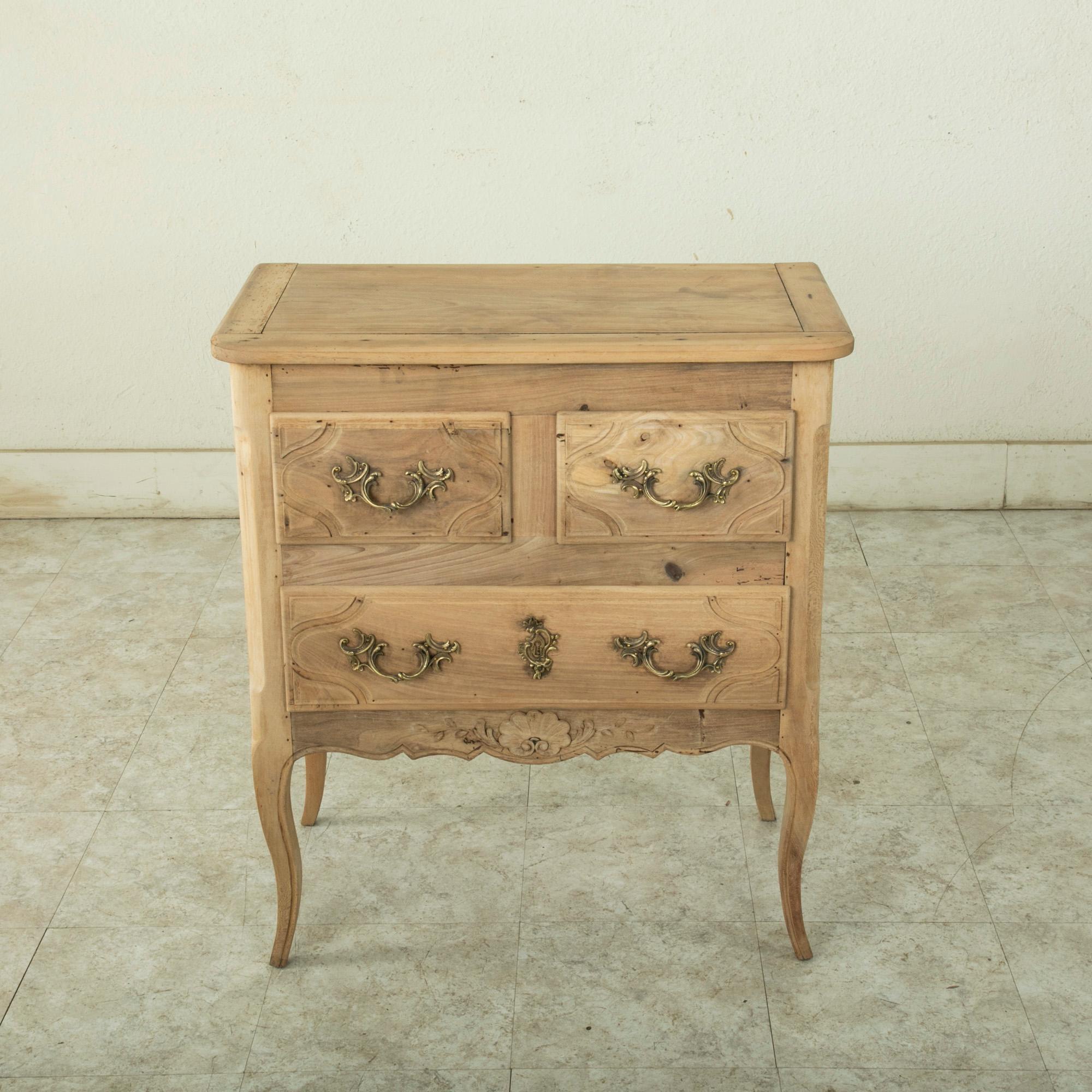 This small scale early twentieth century French Louis XV style beech wood commode or chest features hand carved details of gadrooning leaves and a central shell on its lower apron. Three drawers of dovetail construction feature symmetrical fronts