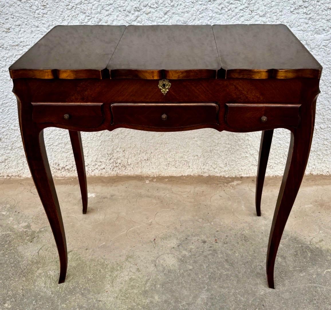 Elégante table de toilette française du début du 20e siècle de style Louis XV, fabriquée en bois richement teinté et se distinguant par ses pieds cabriole raffinés et sa façade serpentine. La pièce est dotée d'un couvercle central qui se soulève