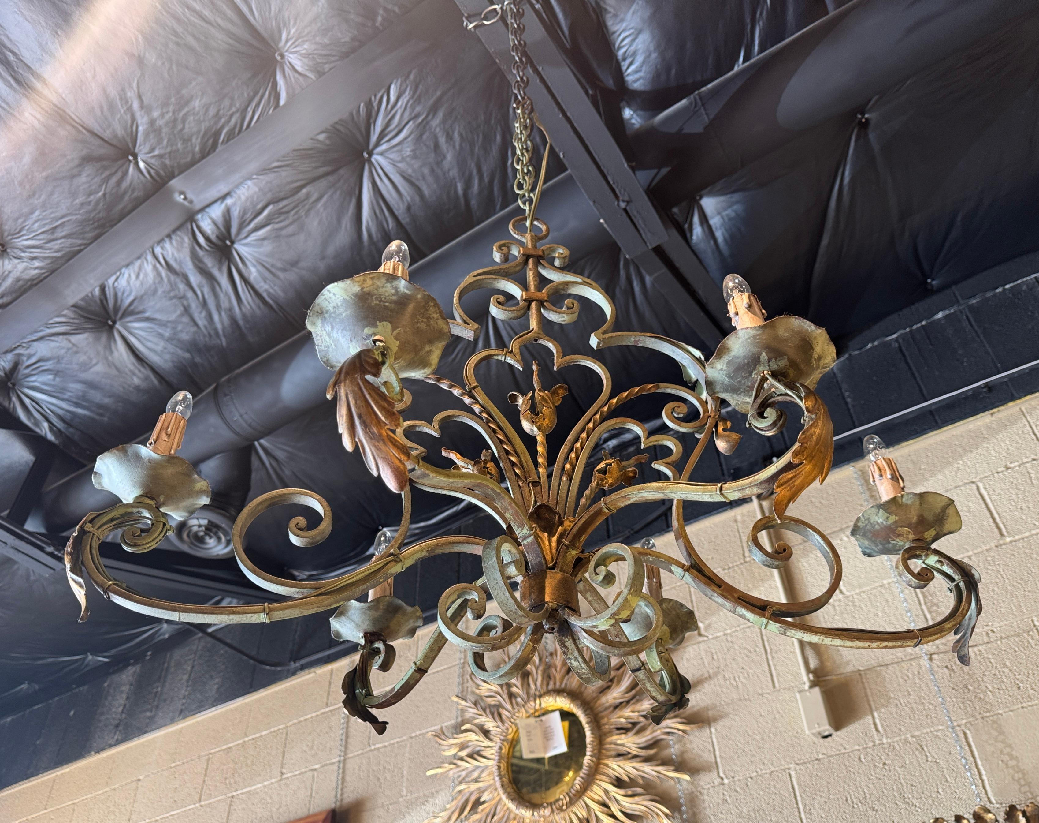 This elegant antique chandelier would make a lovely addition to a breakfast or dining room. Crafted in France circa 1920, and built of iron, the chandelier is oblong in shape. Decorated with metal flowers, acanthus leaves and scroll and twisted
