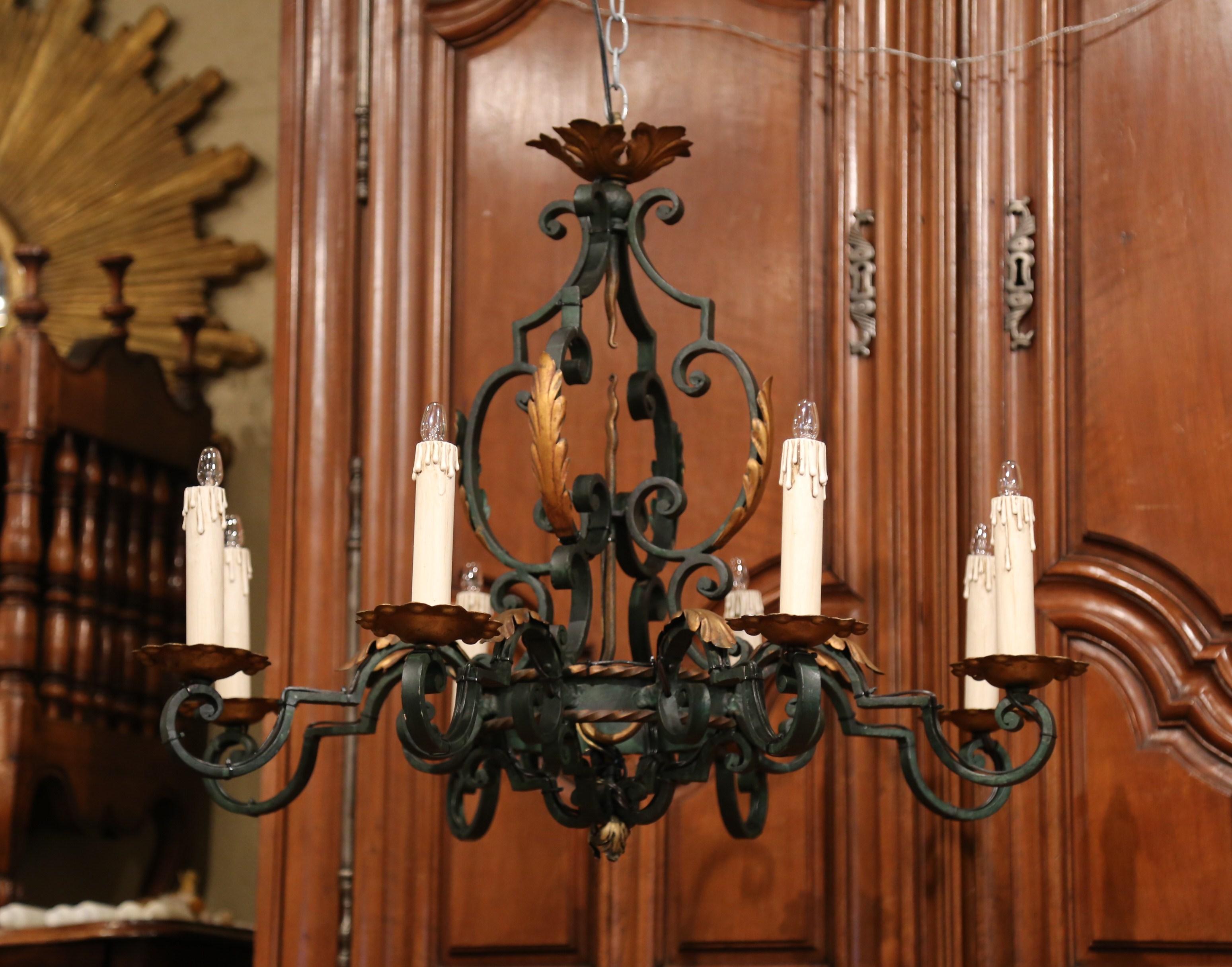This elegant, antique, iron chandelier was created in France, circa 1920. The scrolling, Louis XV style chandelier features its original verdigris with gilt paint accents. Round in shape, the light fixture with decorative central finial, has eight