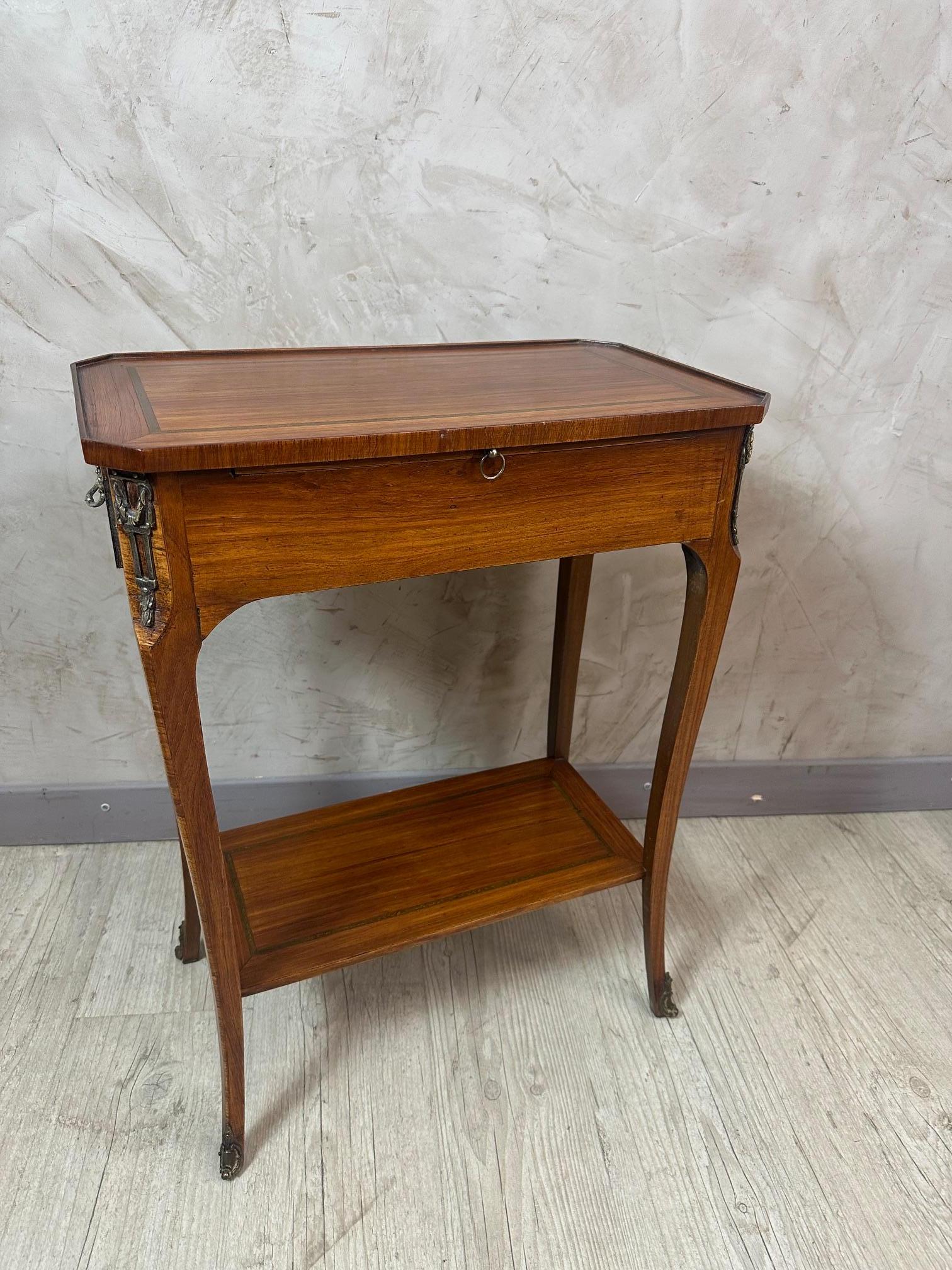 Très belle table d'appoint en noyer datant du début du 20ème siècle en style Louis XV transition Louis XVI.
Deux tiroirs latéraux et une étagère centrale recouverts de cuir noir et vert.
Raccords et poignées en bronze. Superbe qualité.
Sera parfaite