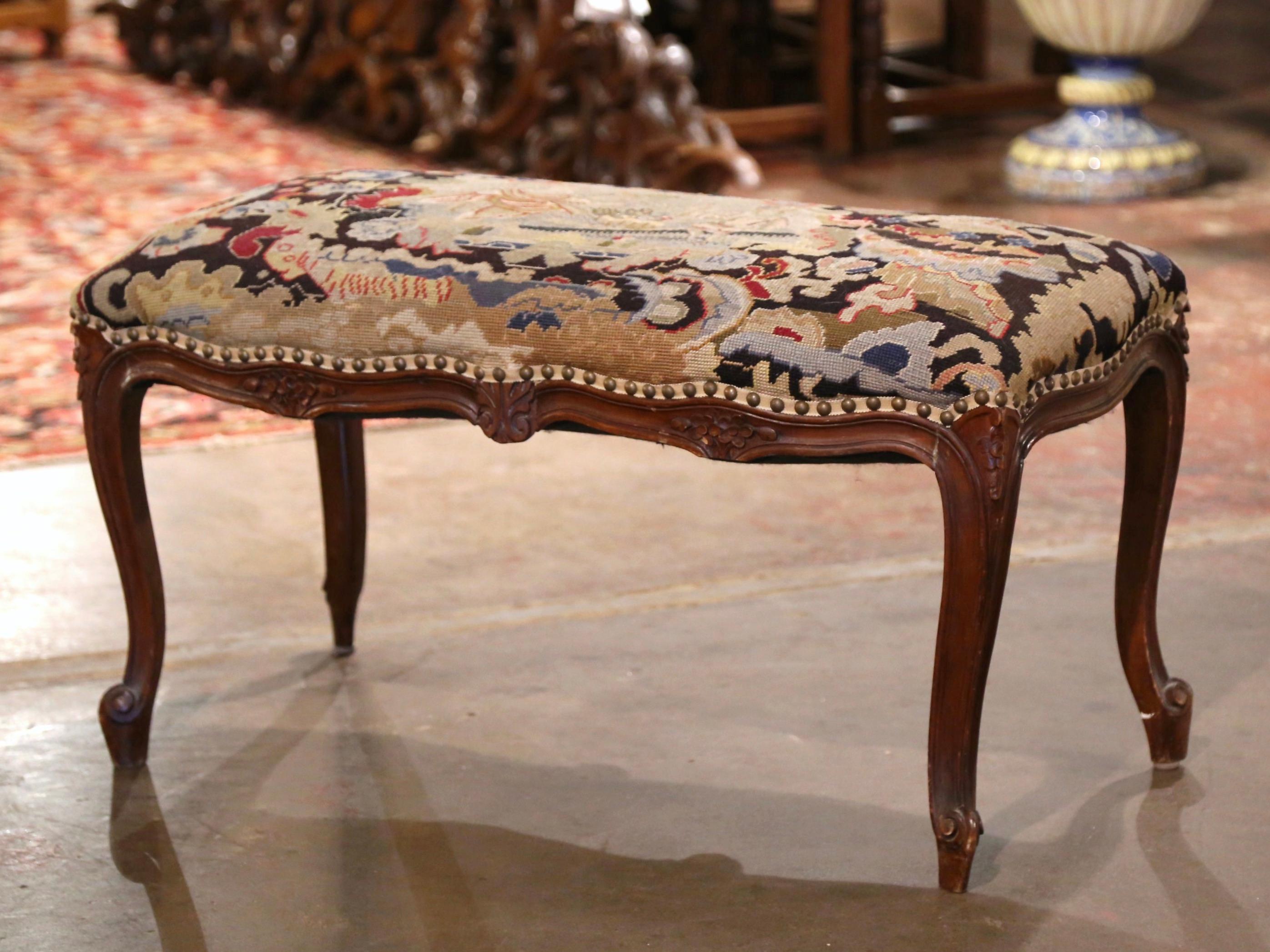 Crafted in Provence, France circa 1920, the antique fruitwood bench stands on cabriole legs decorated with acanthus leaves at the shoulders, and ending with escargot feet. The scalloped and bombe apron on the stool is decorated with a carved shell