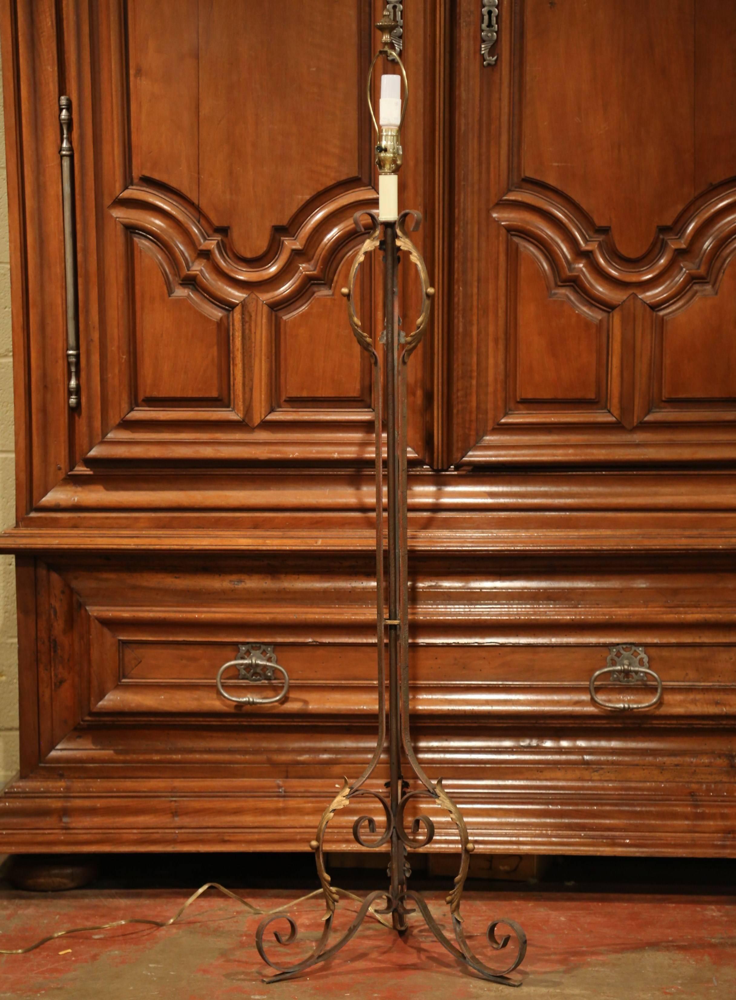 This elegant antique floor lamp crafted in France, circa 1920 would make a beautiful, rustic addition to a living room or study. The single light fixture lamp has been re-wired and features a beautiful, scrolled iron base resting on three legs. The