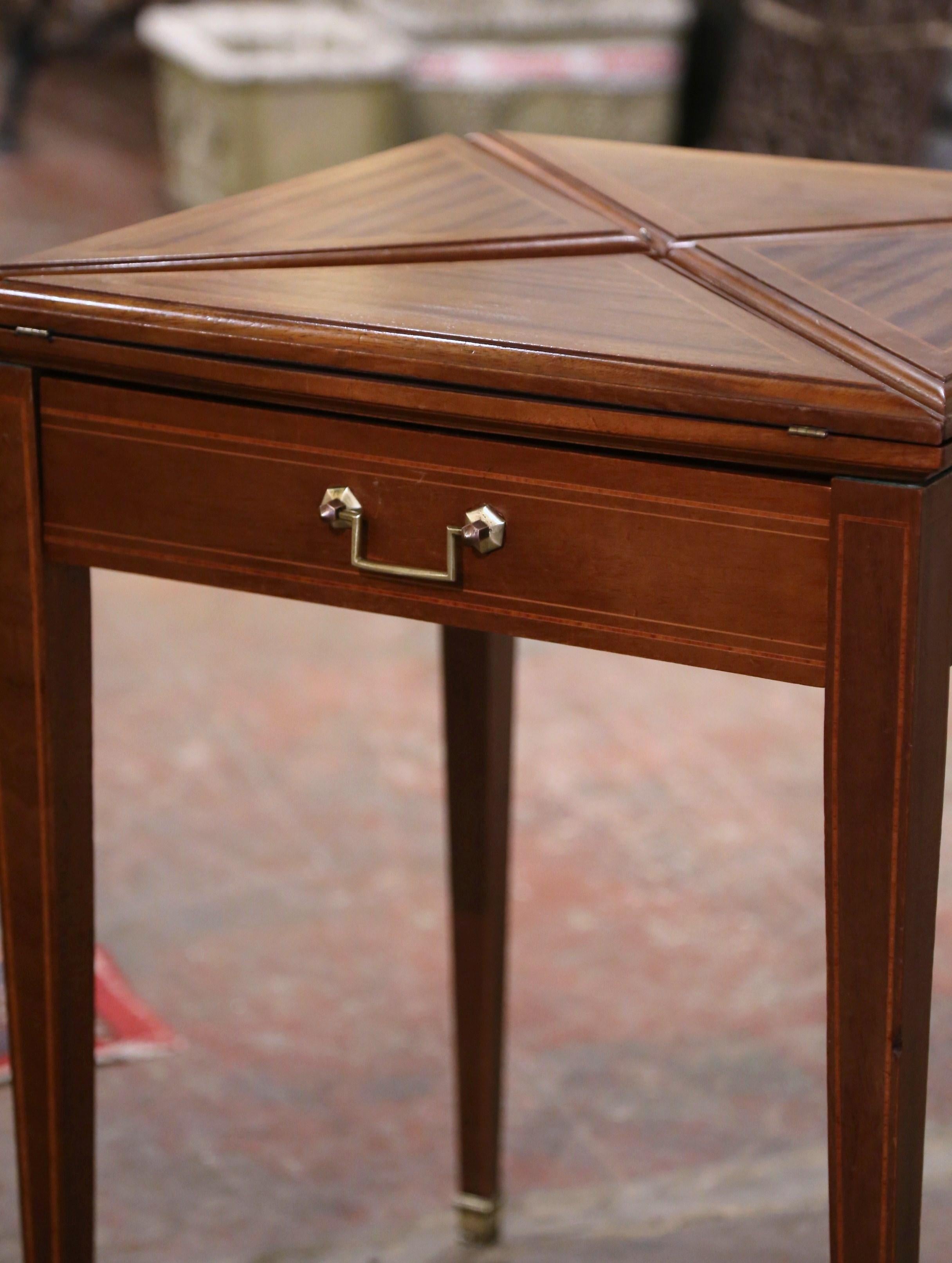 Decorate a game room or a den with this elegant folding card table. Crafted in France circa 1930 and built of mahogany wood with marquetry bands throughout, the square table stands on tapered legs ending with bronze feet covers, over a straight