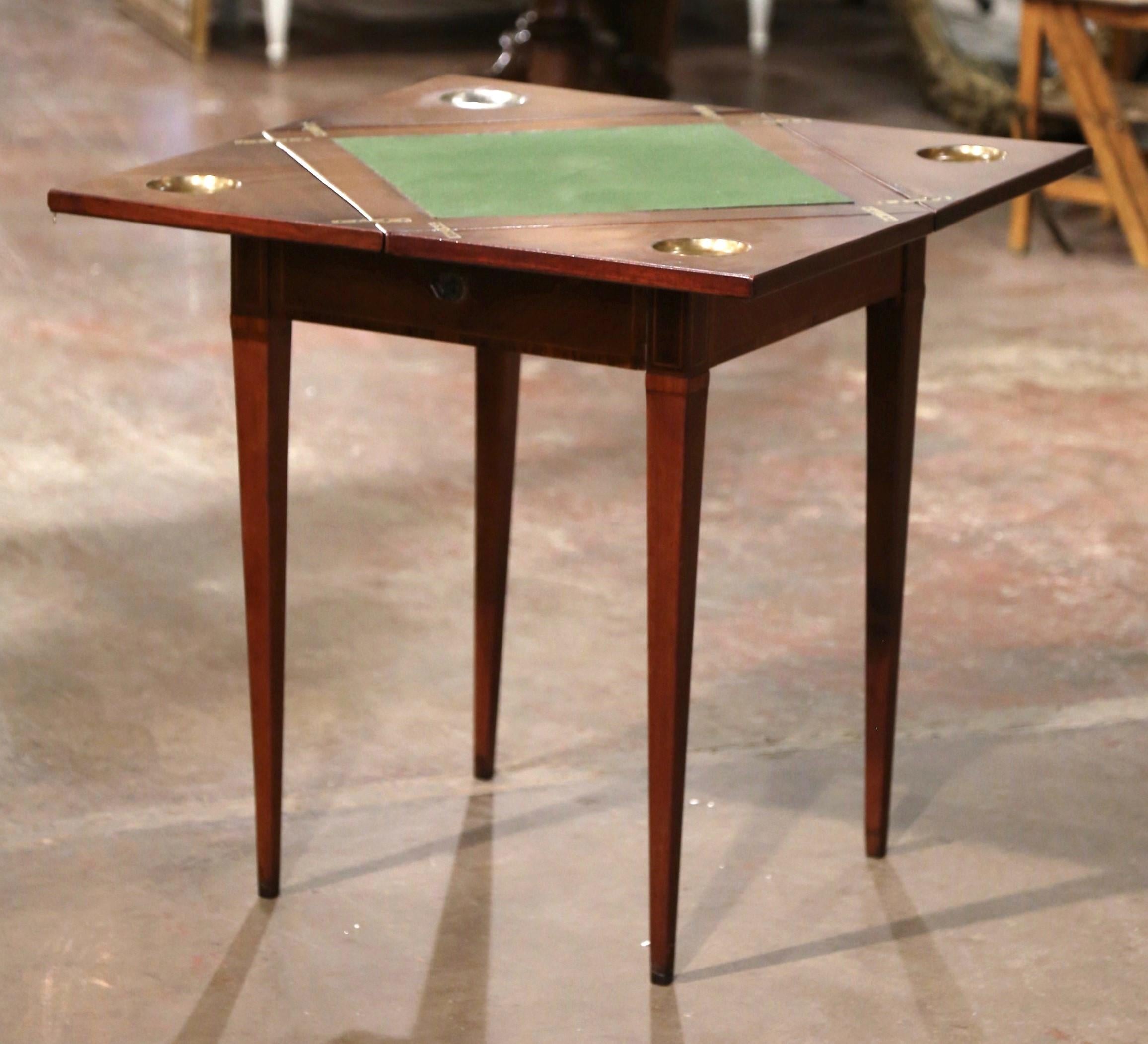 Decorate a game room or a den with this elegant folding card table. Crafted in France circa 1930 and built of mahogany wood, the square table stands on tapered legs, and dressed with a single drawer with chip storage compartments inside; the table