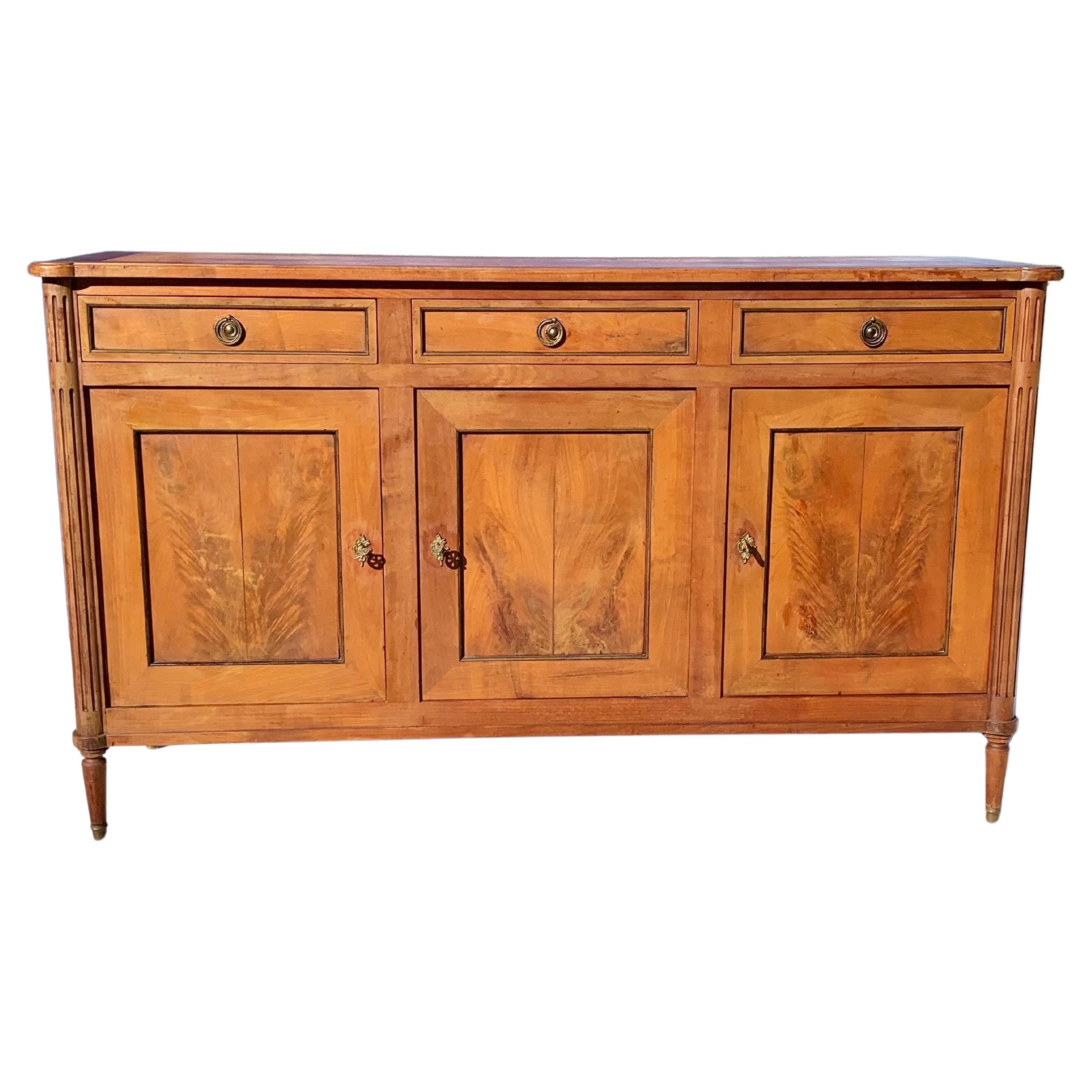 Found in the South of France, this Early 20th Century French Buffet or Sideboard was crafted in the grand Louis XVI style from Cherrywood in the early 1900's.  The piece features a planked top resting above three hand dovetailed drawers and three
