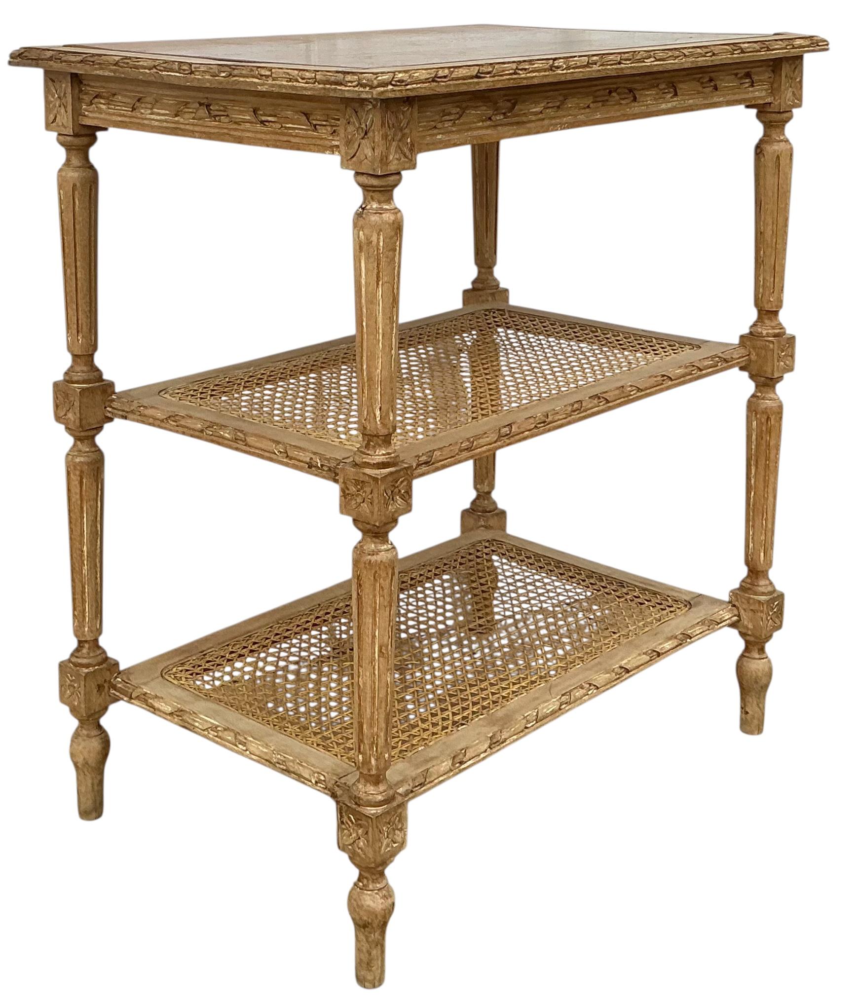 This is a charming early 20th century French Louis XVI carved and caned side table. The caned shelves are in very good condition. I am happy to provide glass for protection. The pine wood has been cerused intentionally. A charming addition to any