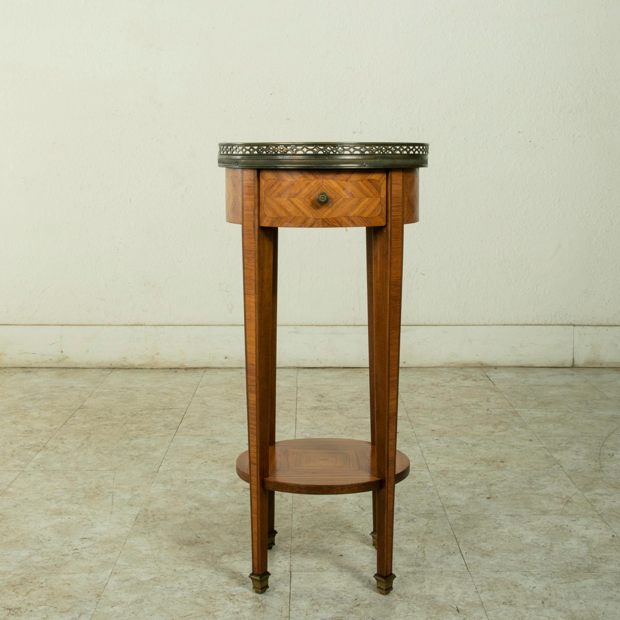 This small scale early twentieth century French Louis XVI style rosewood marquetry side table features a marble top surrounded by a pieced bronze gallery. The rosewood marquetry on each side is divided in quarters with alternating grain patterns