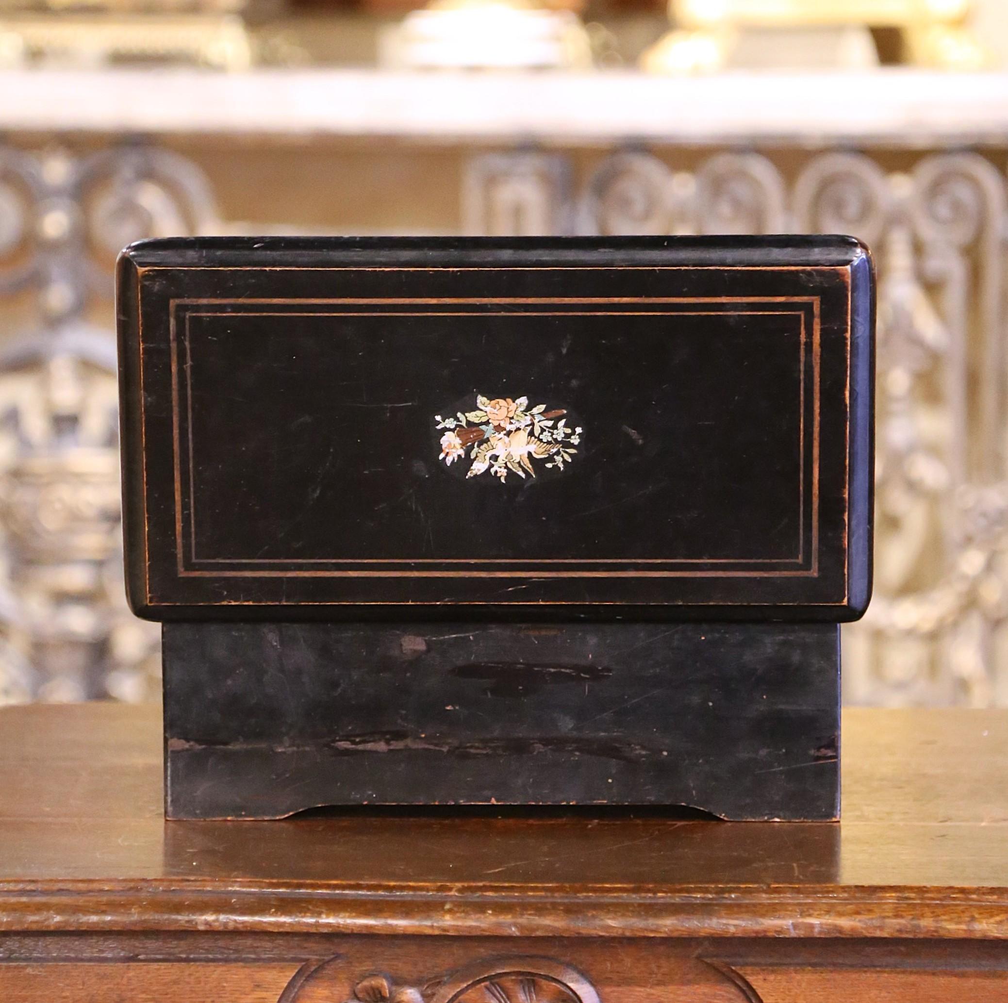 Listen to soft, cheerful music in your living room with this traditional, antique music box. Crafted in Paris, France circa 1920, the  wood case with inlaid decor, has black painted finish and a center hand painted motif featuring two birds holding