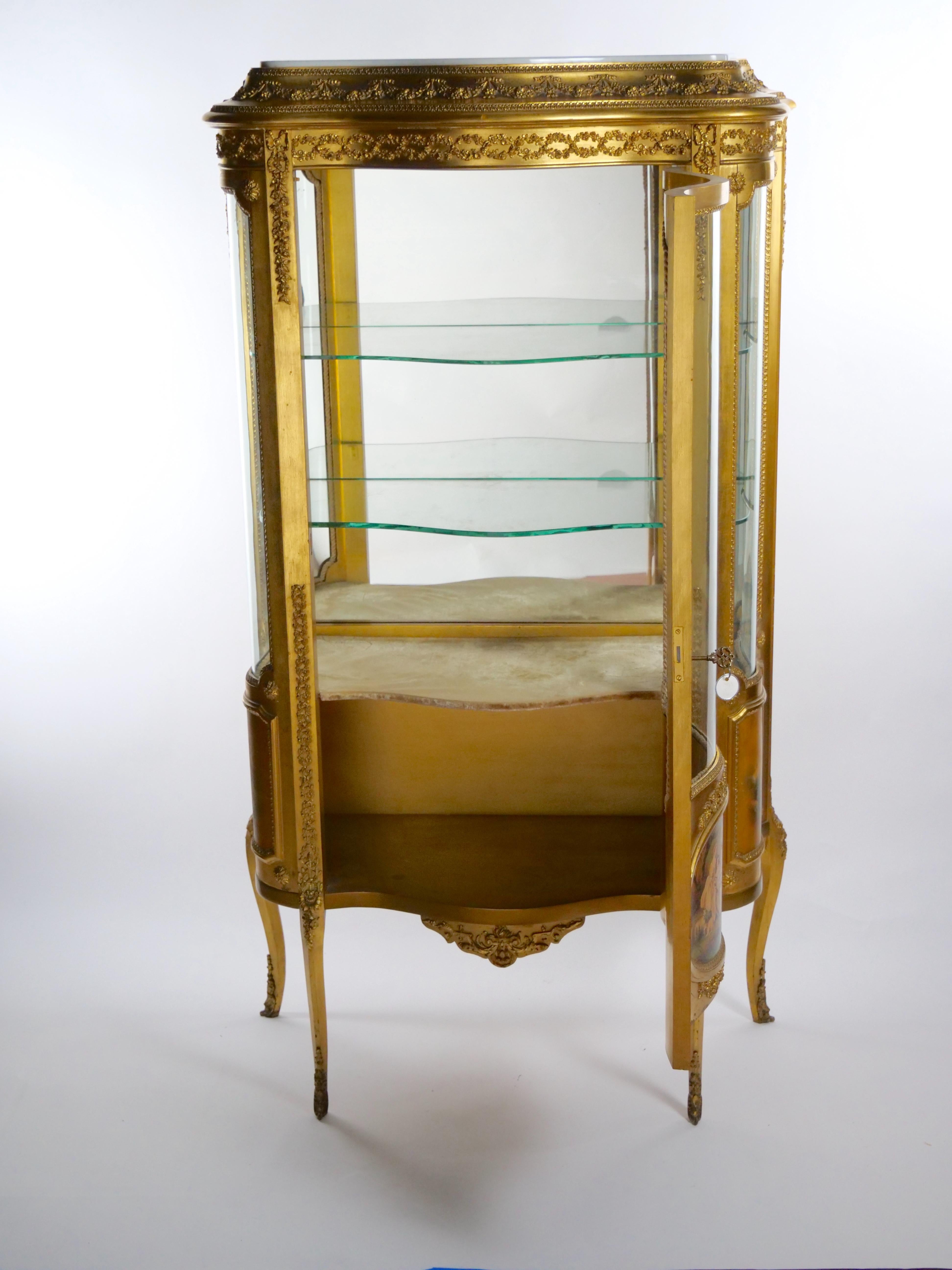 Elegant early 20th century hand painted and gilt gold decorated showcase / display cabinet. The showcase features an oval and rounded painted wood side with glass panels, lacquered, gilded and hand painted wood with very pleasant courtship scene