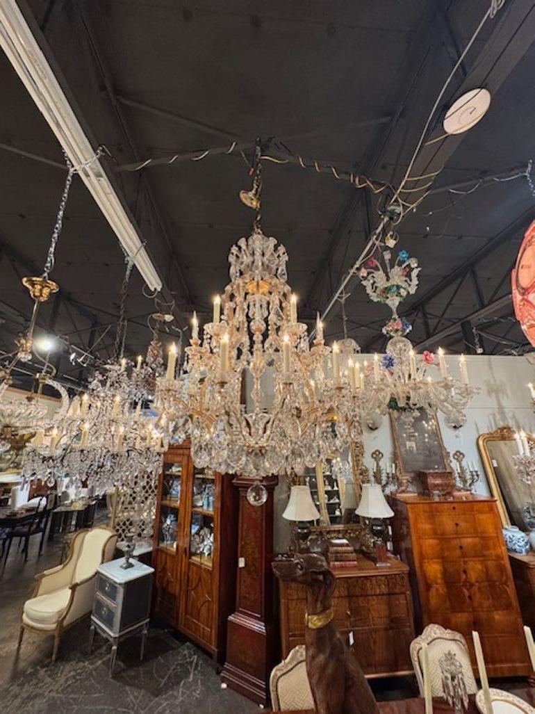 Ce lustre français du début du XXe siècle est conçu dans le style Marie-Thérèse, connu pour ses détails de cristal élégants et complexes. Le lustre présente une étonnante exposition de cristaux qui reflètent magnifiquement la lumière, ajoutant une