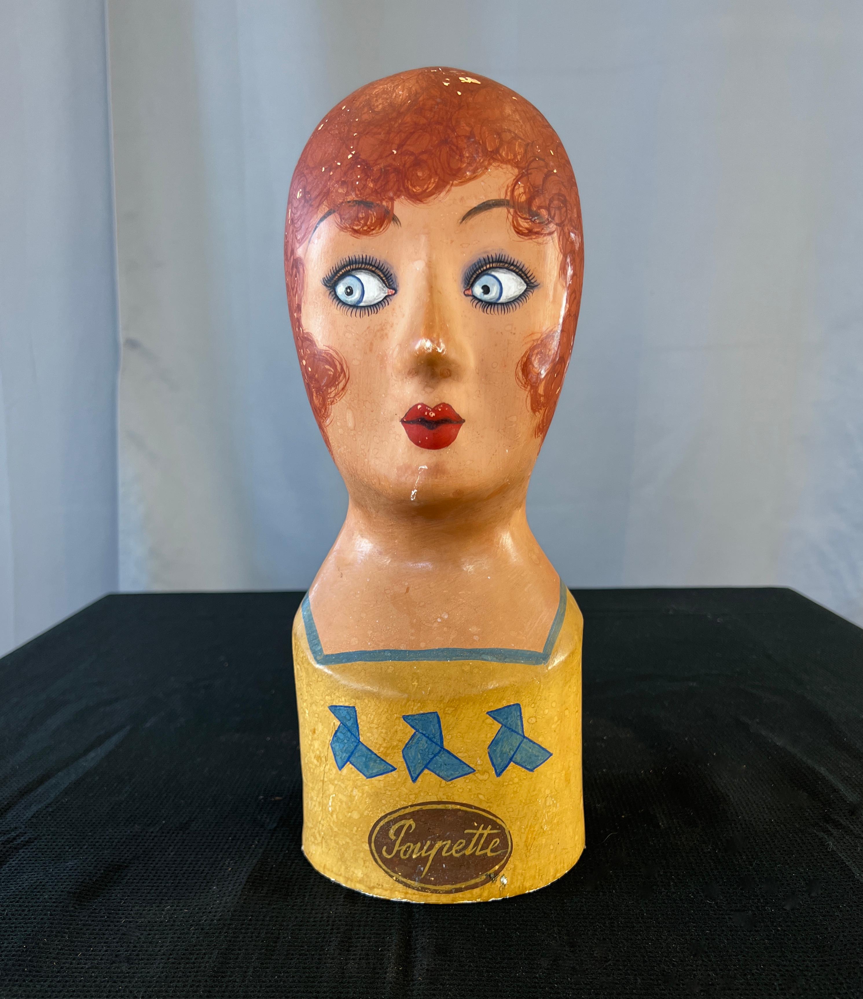 A wonderful paper maché French marotte or milliners head.
In front of the head, word Poupette(?) presumably the store she was made for,
with 