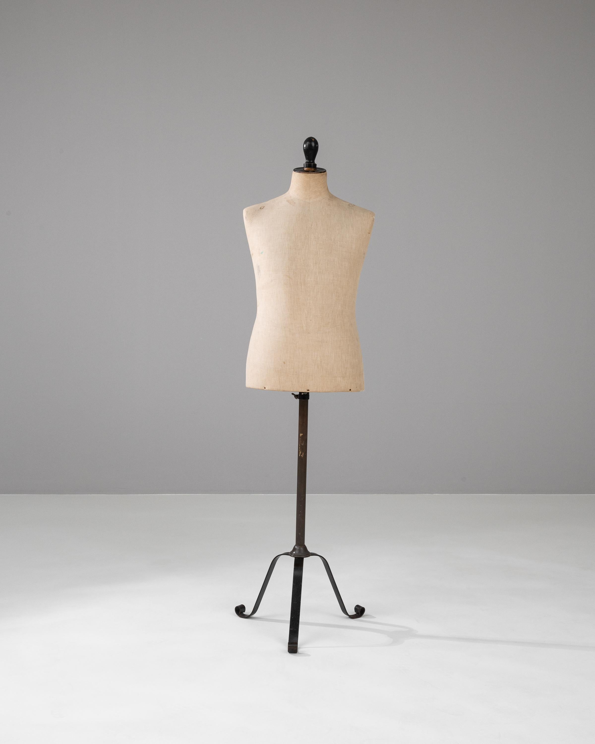 Capture the essence of early 20th-century French craftsmanship with this Antique French Metal Mannequin. Crafted with precision, this unique piece showcases the silhouette of a woman and stands on a turned stand with a weathered tripod base. The