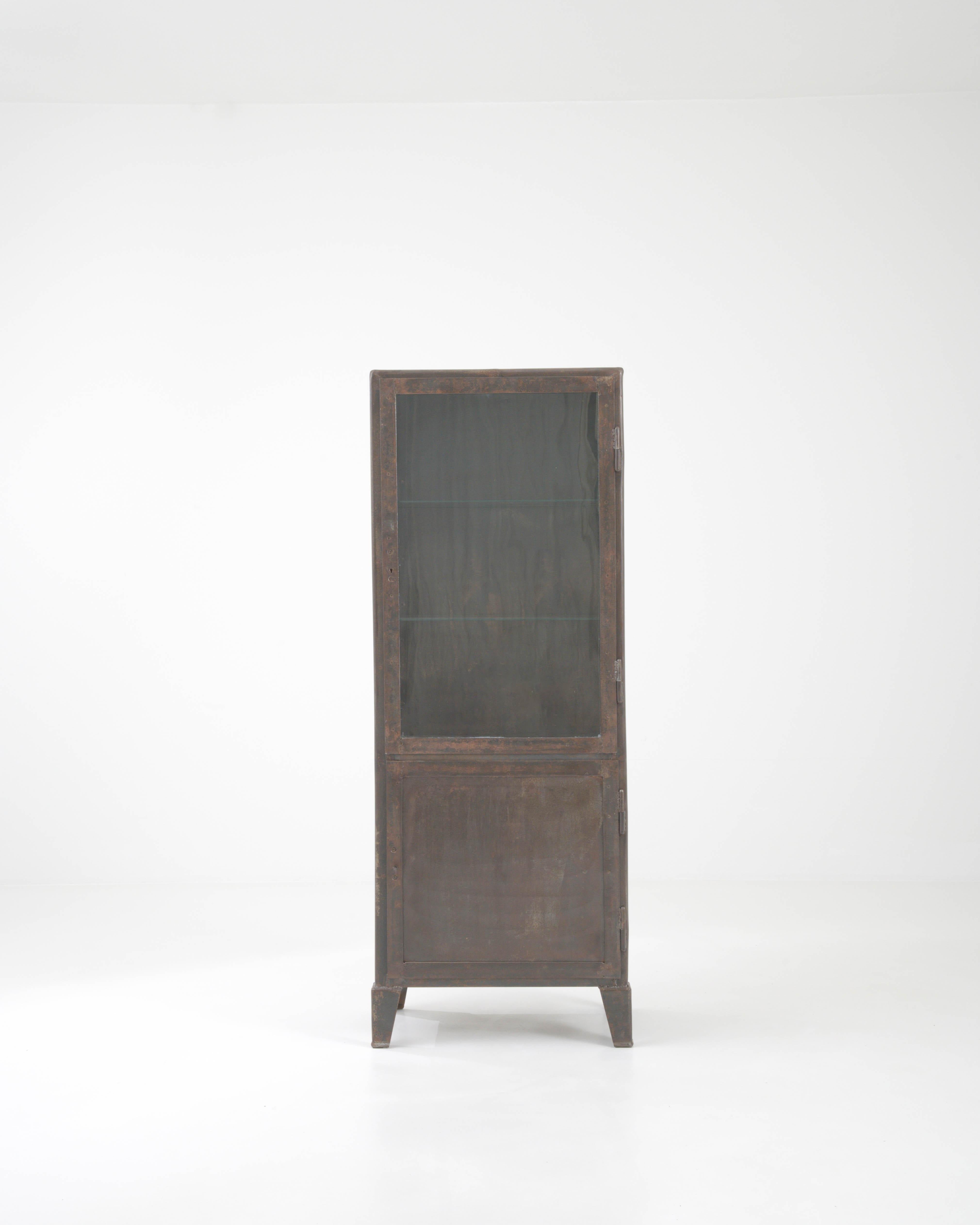 Step back in time with this early 20th-century French metal vitrine, a piece that marries industrial practicality with the grace of a bygone era. With its robust metal construction, this cabinet exudes a character of resilience and authenticity, its