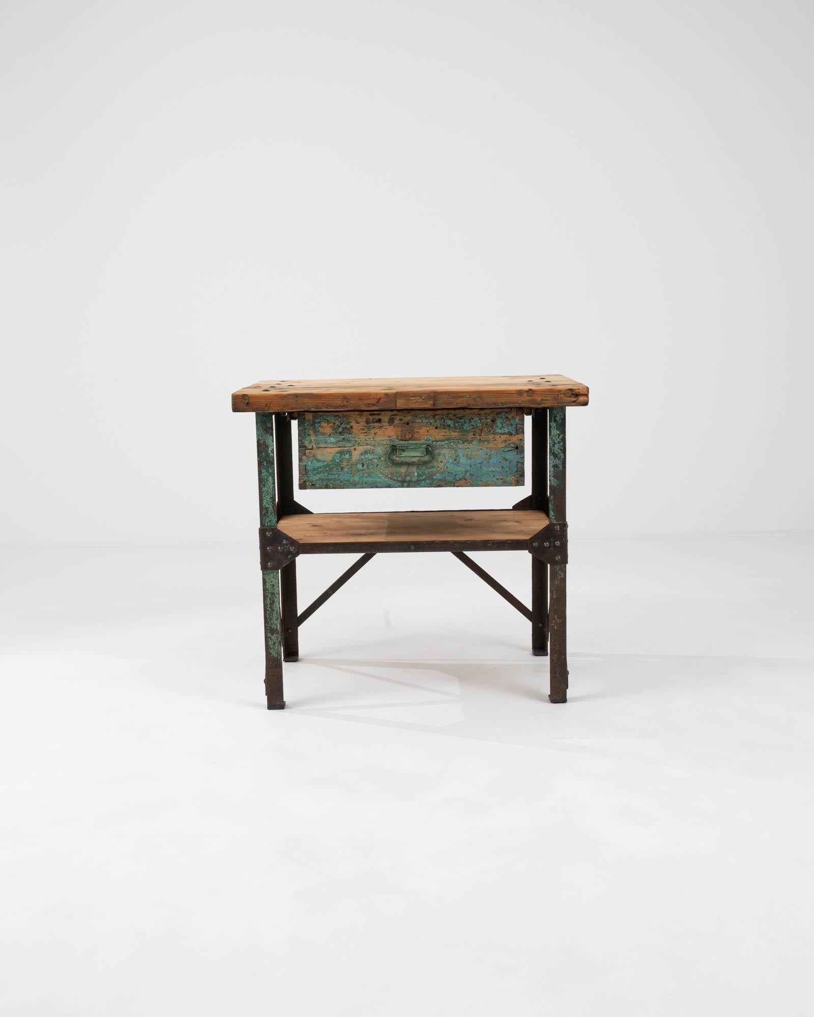 Introducing an exquisite piece of history and craftsmanship: the Early 20th Century French Metal & Wooden Work Table. This robust table stands as a testament to enduring design, featuring a solid wood top that bears the rich patina of time, telling