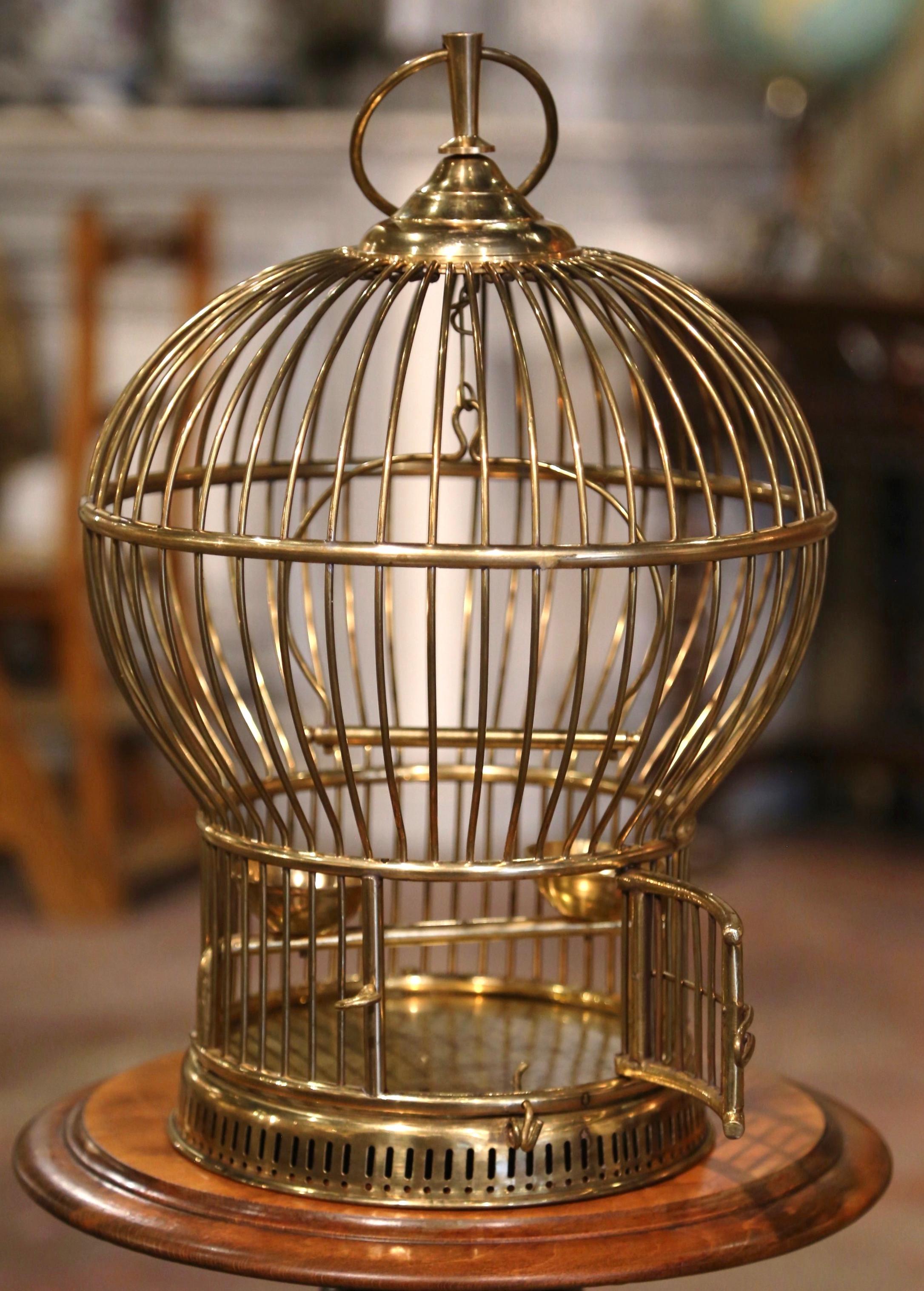 Decorate your home with this whimsical antique bird cage. Crafted in the Alsace Lorraine region of France, circa 1920, this Napoleon III cage made of brass, is cylindrical in shape and topped with a rounded dome embellished with a decorative hanging