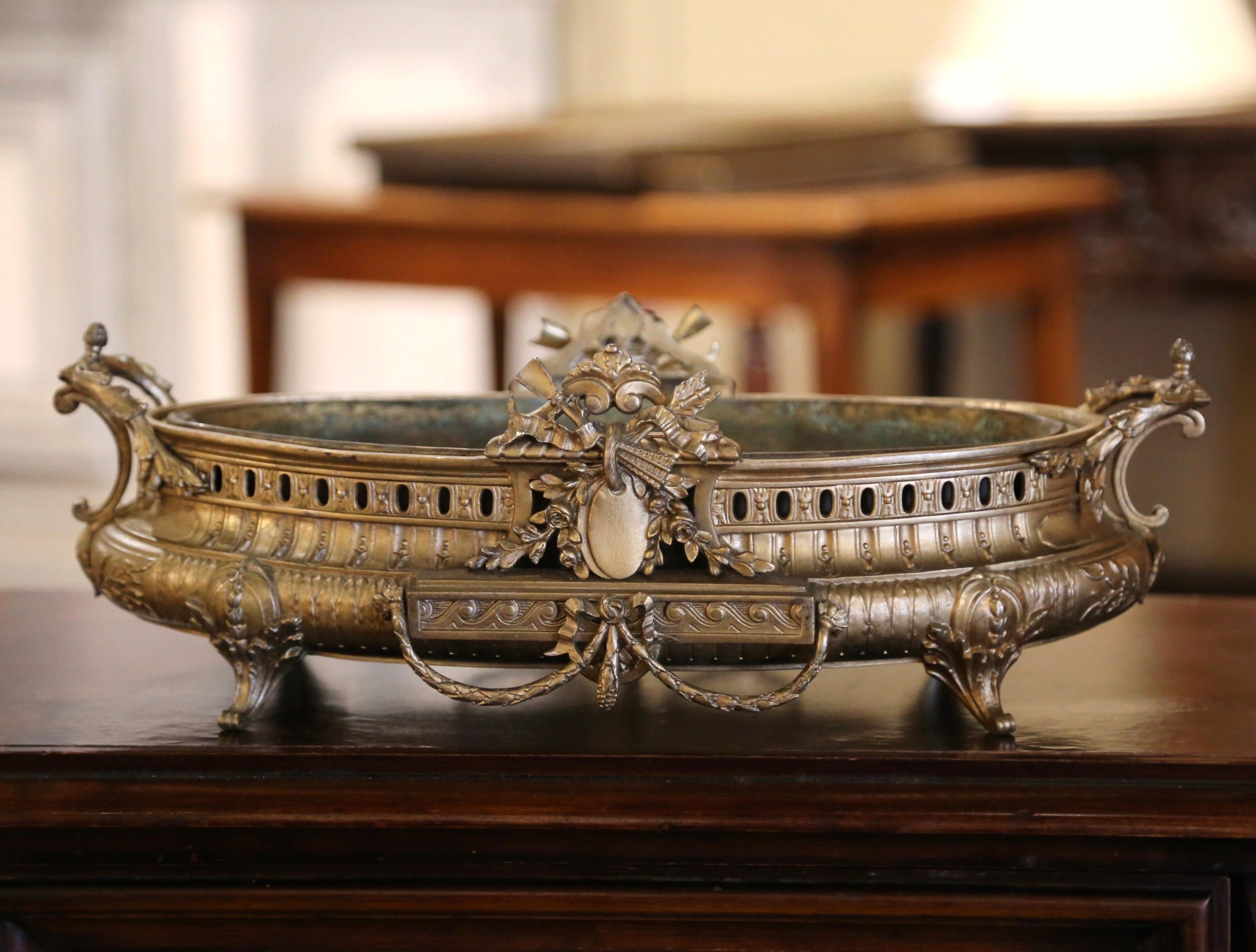 This elegant, antique bronze planter with original zinc liner was crafted in France, circa 1920. With intricate side handles, the planter features a central crest on both sides with floral decor and intricate detailing with ornate motifs throughout.