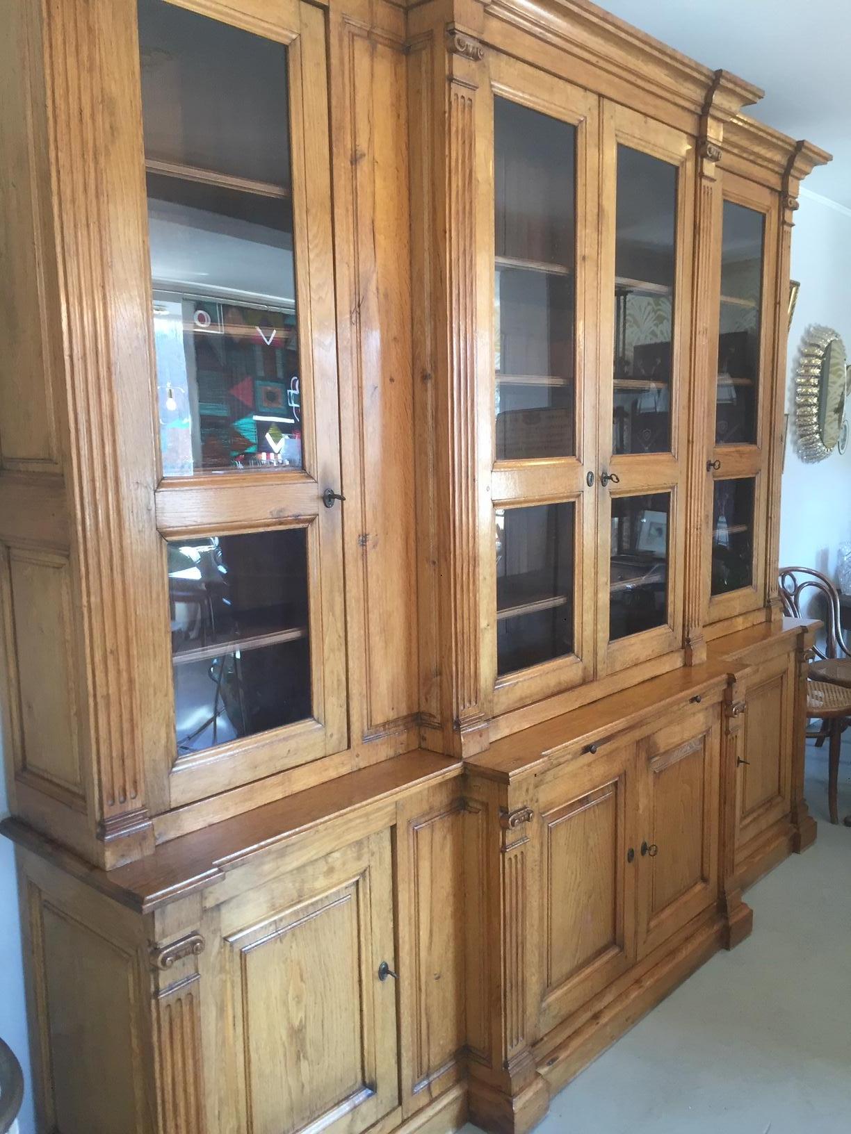 Beautiful 20th century French oak Bibliotheque bookcase in two parts, from the 1900s.
Four glass doors with their originals keys on the top part and four solid doors on the bottom part. A hidden drawbar on the middle of the two parts.
All the
