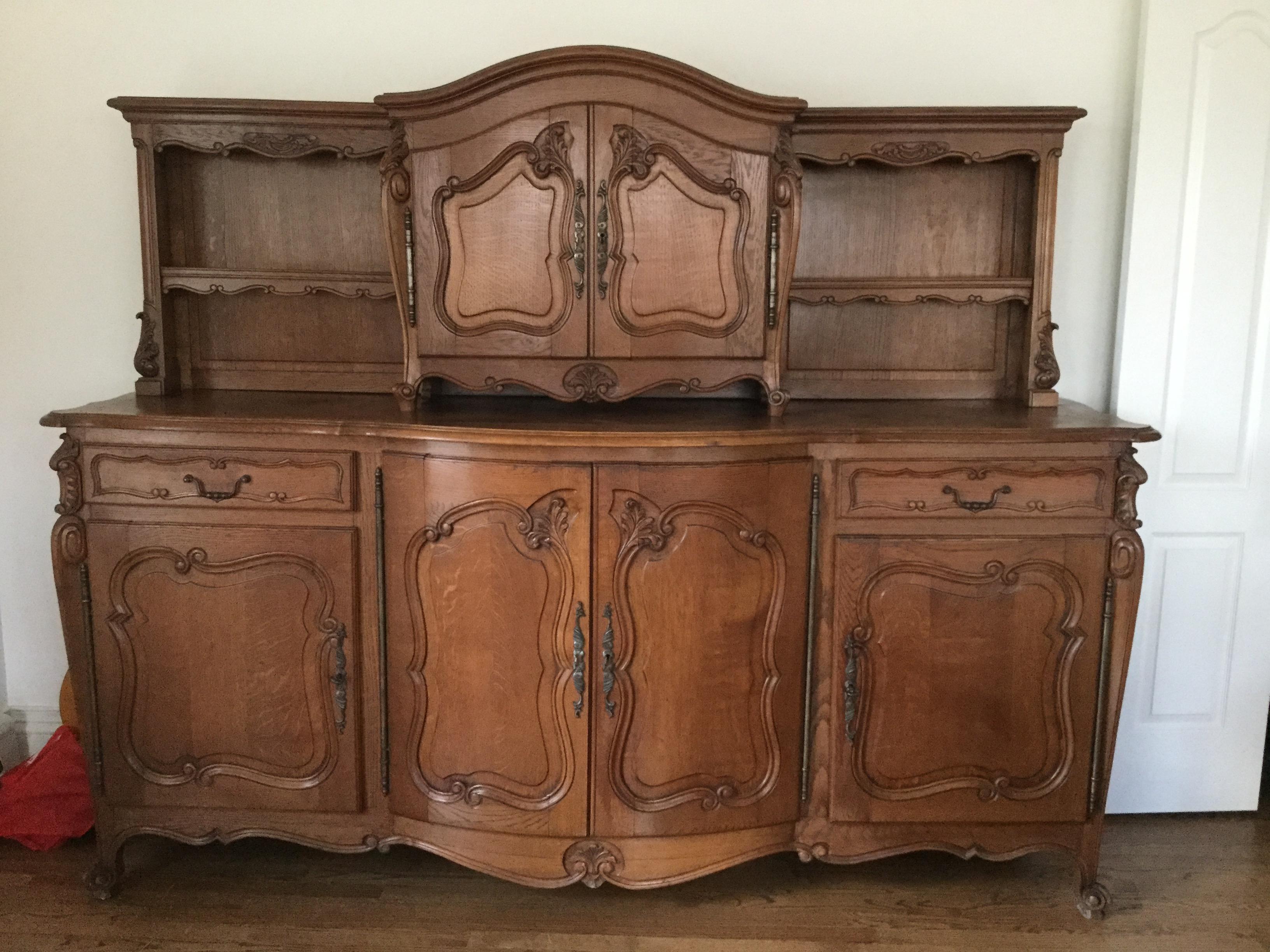 This handsome French sideboard features a large bottom cabinet and a top shelf. Made of solid French oak, this piece has the charm of a rounded front, carved floral motifs and acanthus leaves. With lots of drawers and shelves, this sideboard
