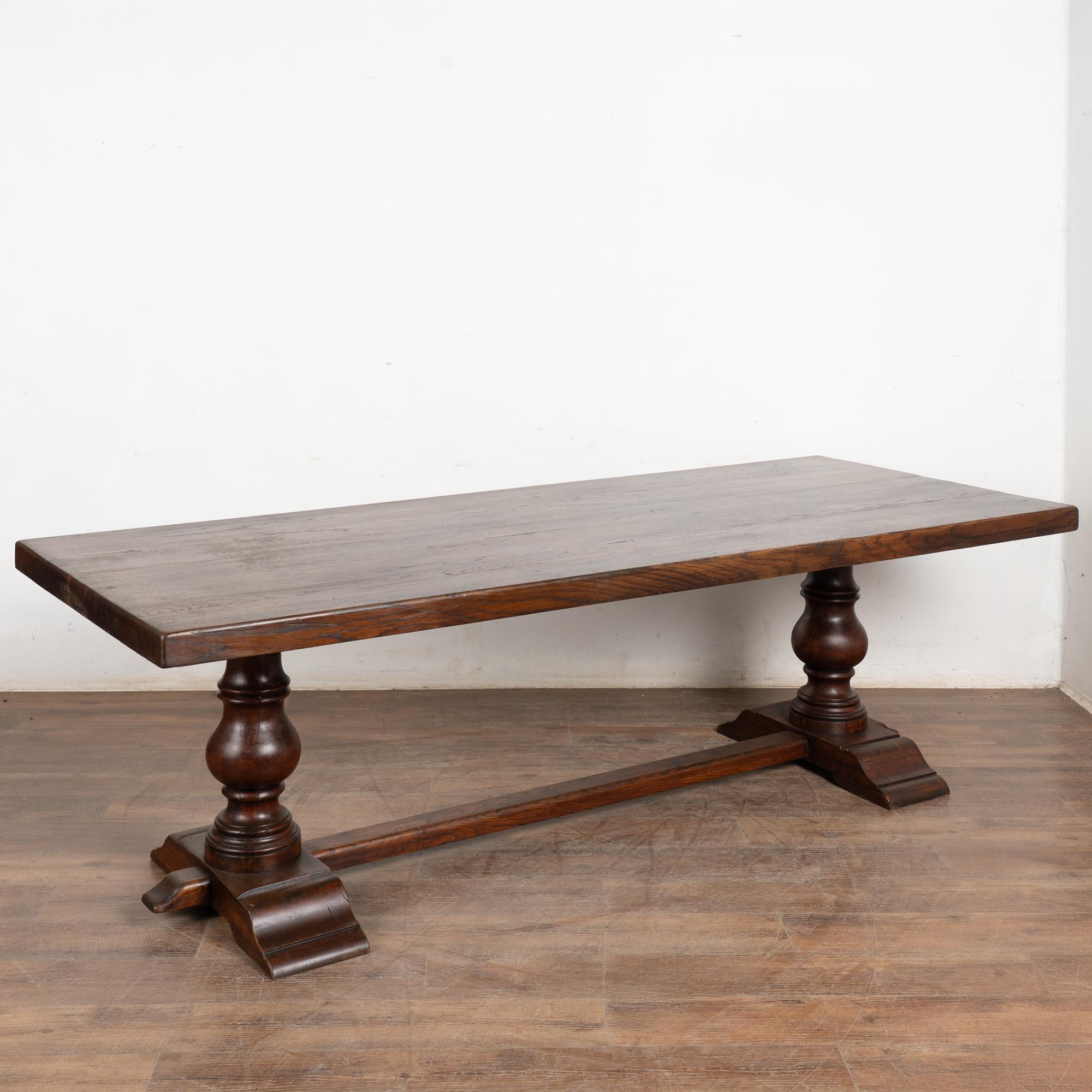 Table de salle à manger en chêne français du début du 20e siècle. Le plateau épais est soutenu par des pieds tournés et une solide base à brancards. Huit à dix places assises selon la disposition des chaises. Les entailles, rayures et fissures liées