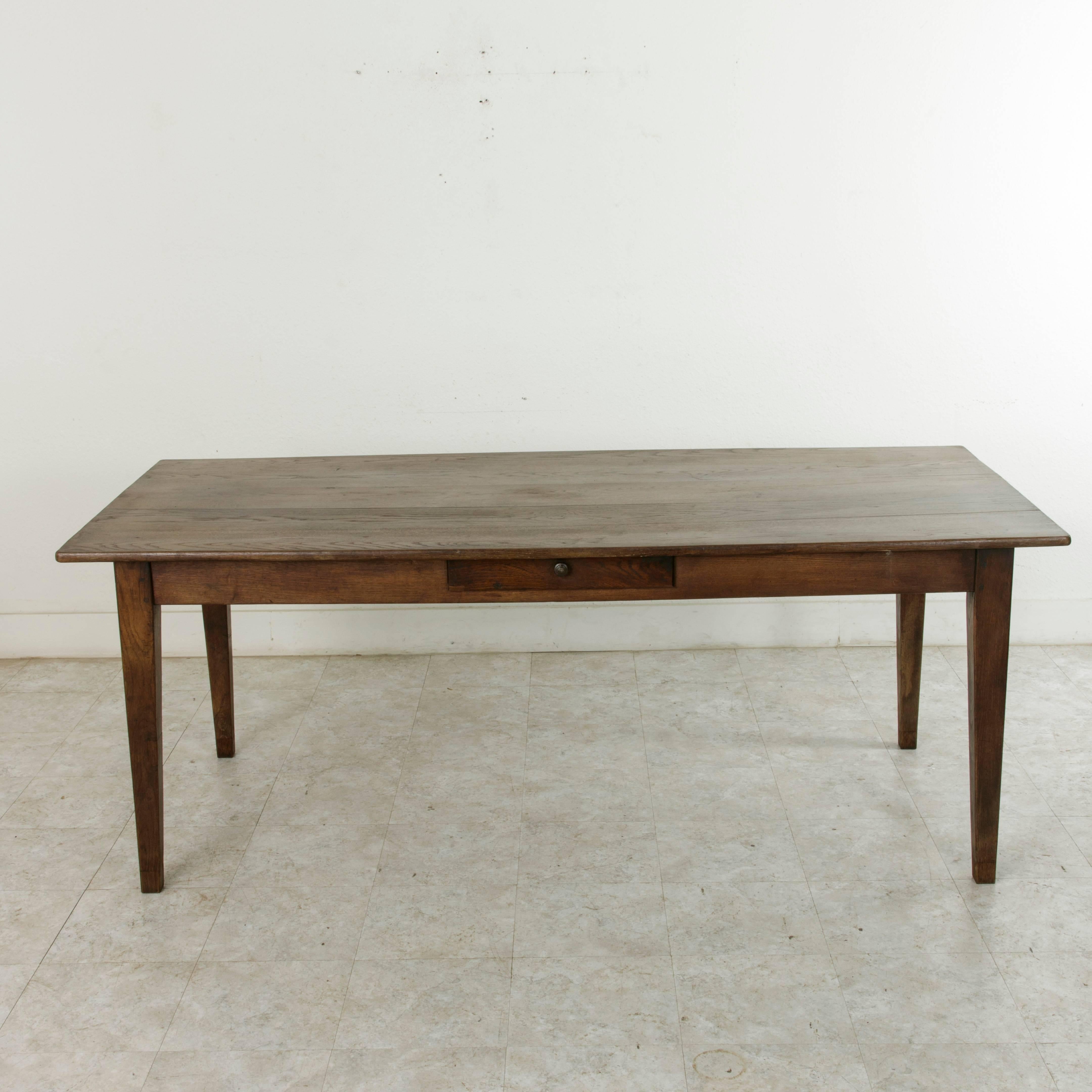 This handsome French oak farm table or dining table from the early twentieth century features a top constructed of five planks of wood resting on a hand pegged base with gently tapered legs. From the region of Le Perche, a Sub-region of Normandy,