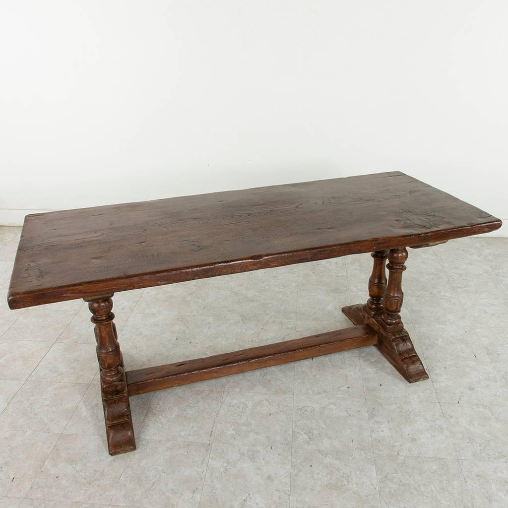 This early 20th century oak monastery table or farm table from the region of Normandy, France, features a 30-inch wide solid top made from a single plank of wood. Quite a tree! This sturdy top rests on a base formed by double column turned legs at
