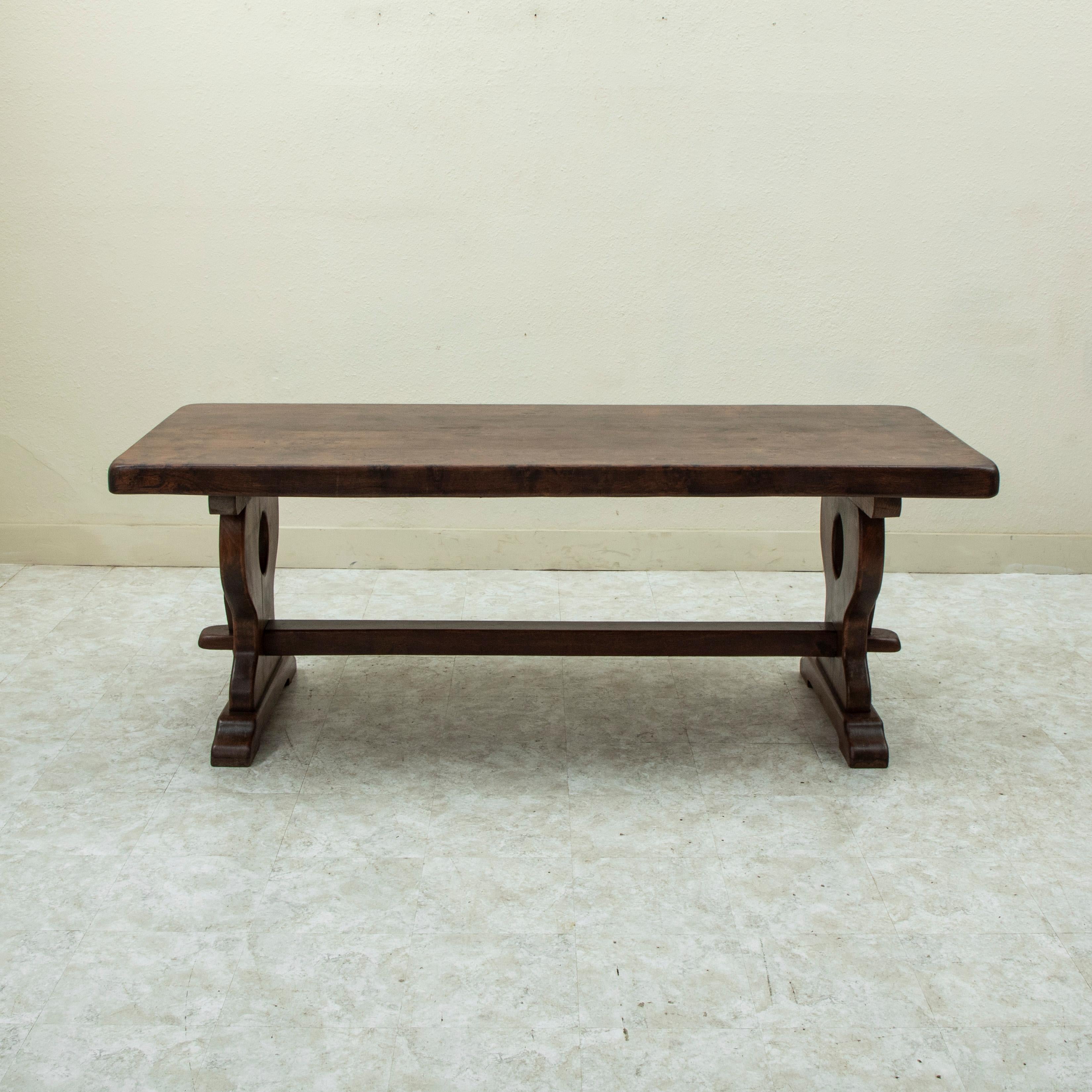 Found in the region of Normandy, France, this large early twentieth century artisan-made oak monastery table or dining table features an impressive 3 inch thick top constructed of four planks of wood. The table rests on a sturdy trestle base