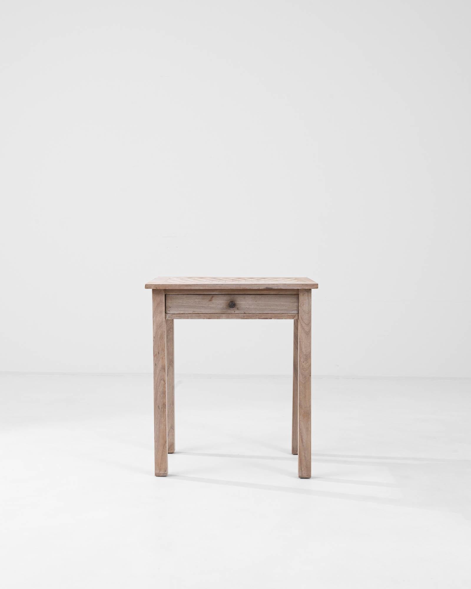 A clean composition and a beautifully crafted tabletop give this vintage oak side table a unique character. Hand-made in France in the early 20th century, the silhouette is simple and linear. The neat corners of the square tabletop mirror the neat