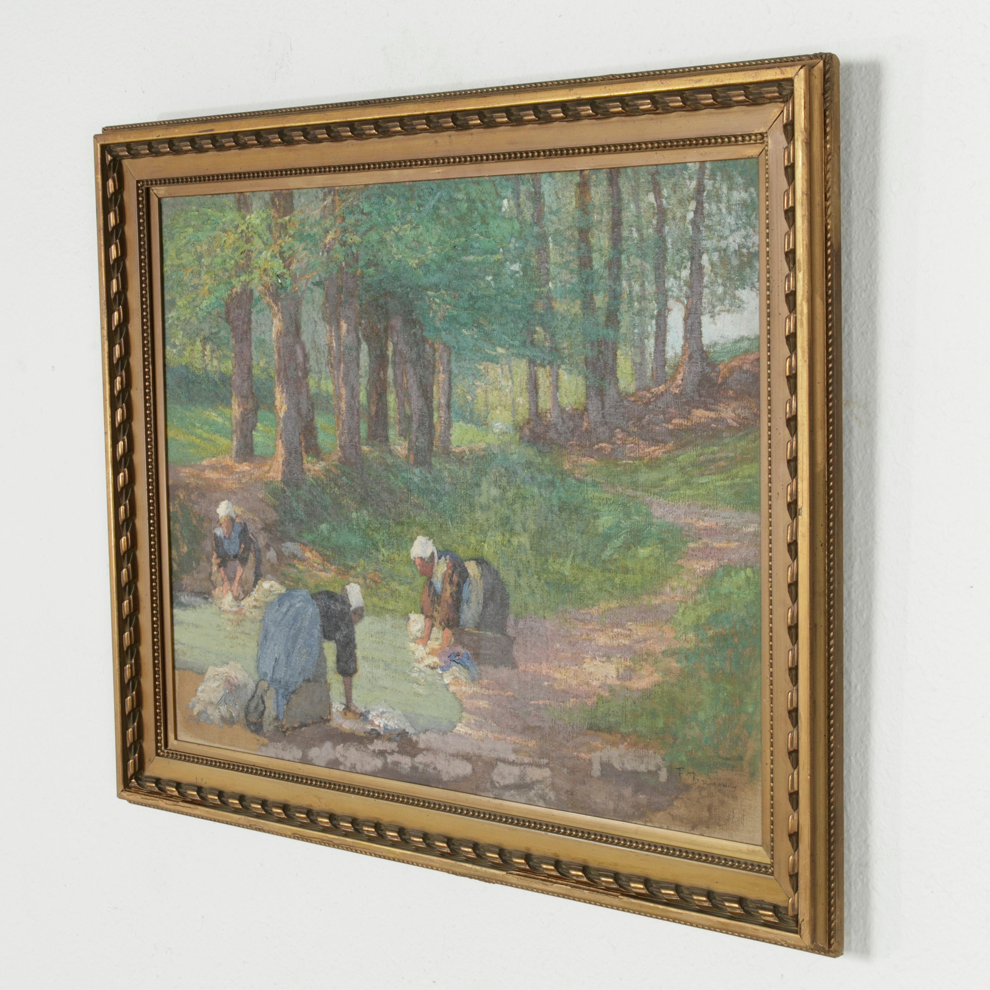 Measuring 24 inches in height and 32 inches in width unframed, this large oil on canvas painting from the early 20th century depicts a pastoral scene at the riverside. In the lower left are three laundresses at work. Signed by the artist, this