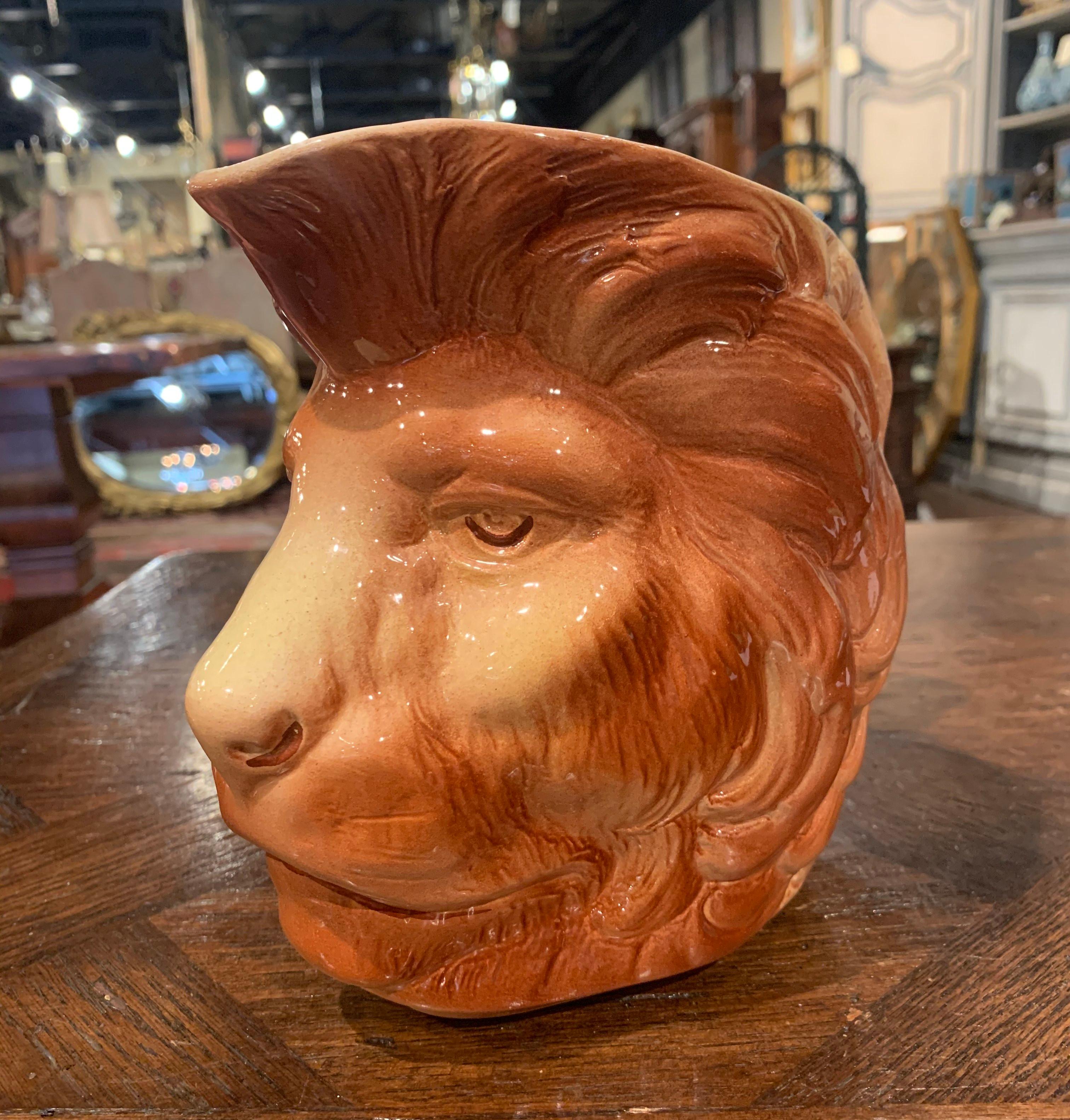 Decorate a shelf or a kitchen counter with this elegant Majolica antique pitcher. Created in Saint Clement, France circa 1930, the pitcher features a lion head. The water jug is in excellent condition with rich colors in the brown palette. Stamped
