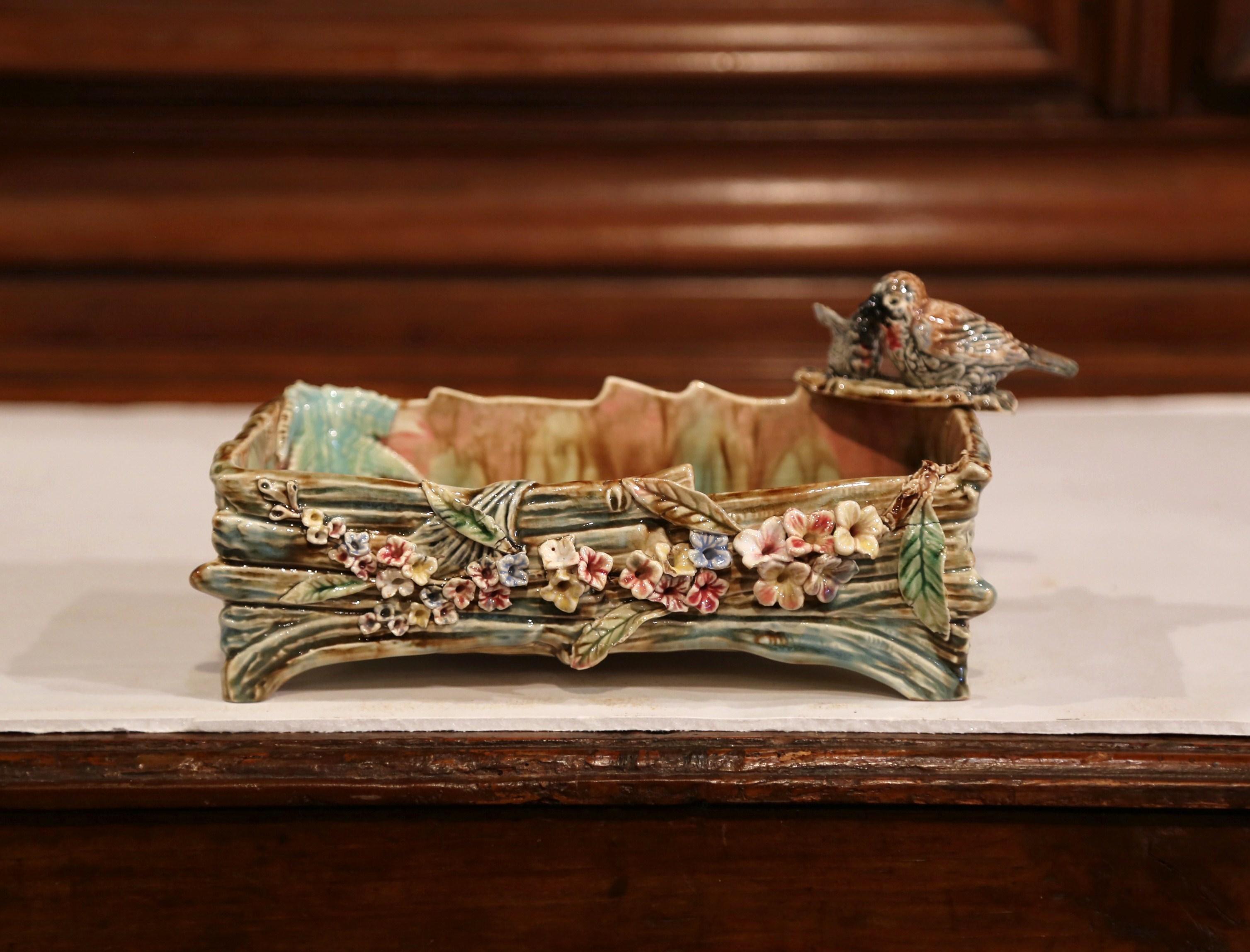 This antique colorful majolica planter was created in France, circa 1920. The rectangular cache pot is decorated with foliage decor and features two birds standing in one corner. The front of the ceramic dish is embellished by small flowers in high