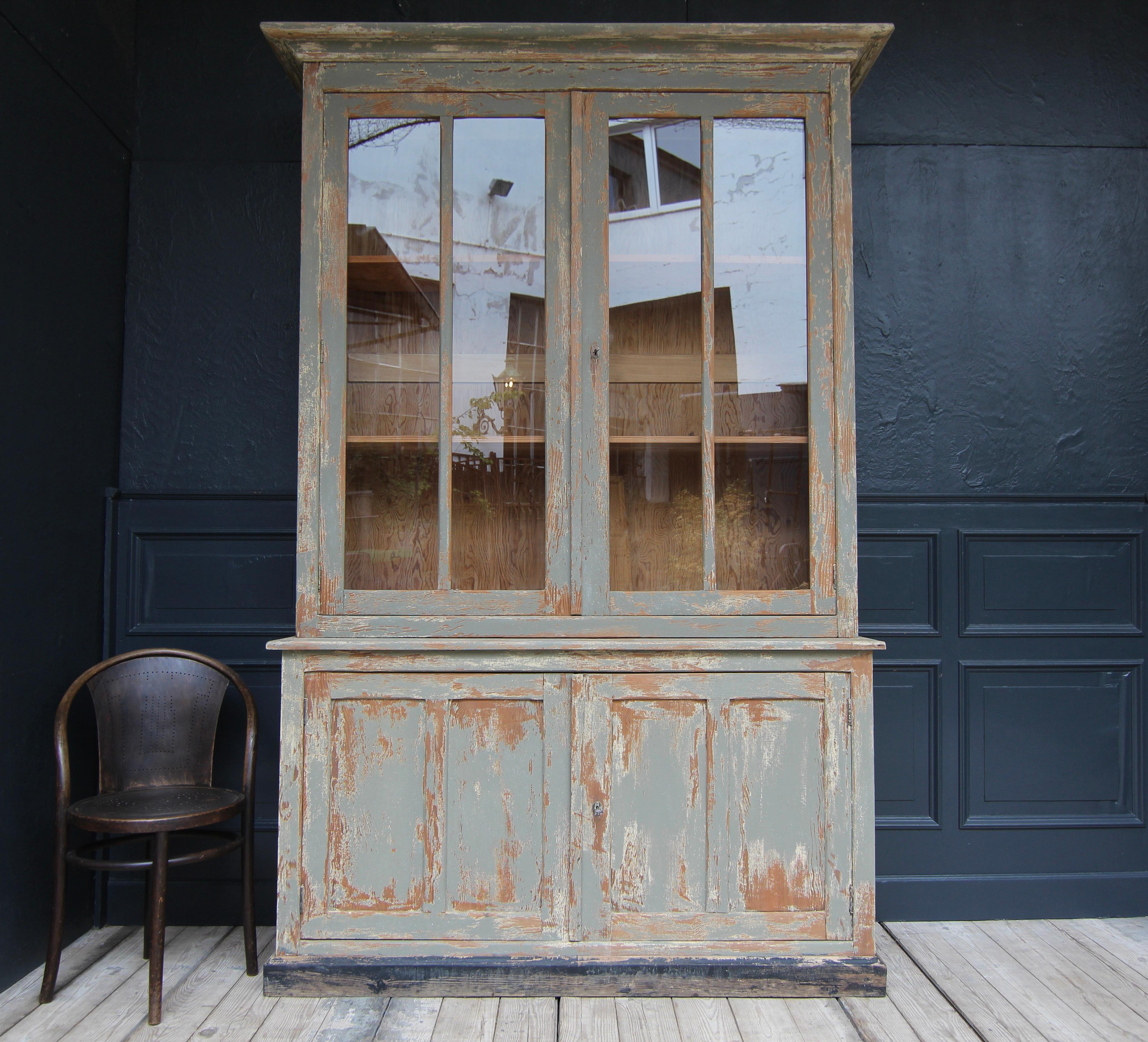 Large French display cabinet à deux corps from the early 20th century. Made in pitch pine wood with stunning patina. 

Comprising a two door base cabinet and a tall display cabinet top with 2 shelves inside adjustable in height on toothed