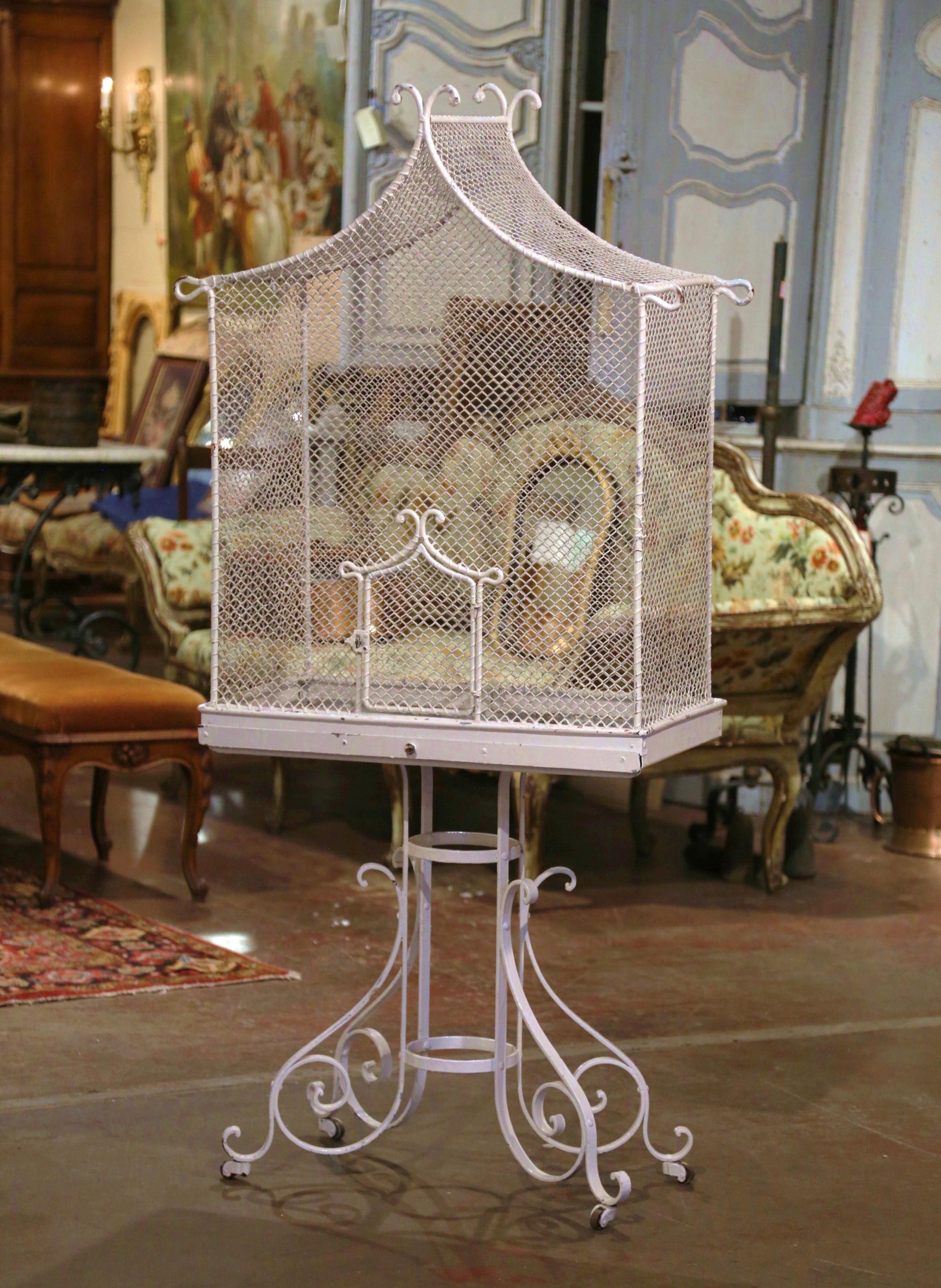 Add color and whimsical charm to your kitchen or breakfast room with this large antique aviary bird cage. Crafted in France circa 1920 and built in two pieces (base and house), the six foot free standing bird house stands on four intricate iron