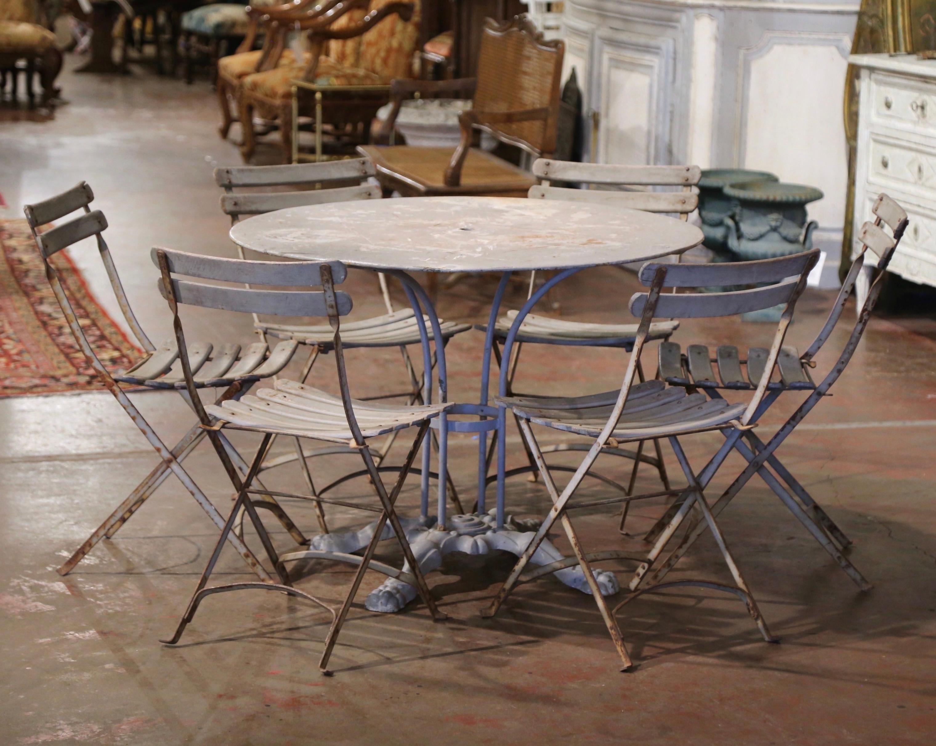 Decorate a patio, a pool area, or sun room with this elegant antique four-leg gueridon iron table. Crafted in France circa 1920, the outdoor table stands on a central pedestal base ending with four legs and paw feet; the legs are joined together