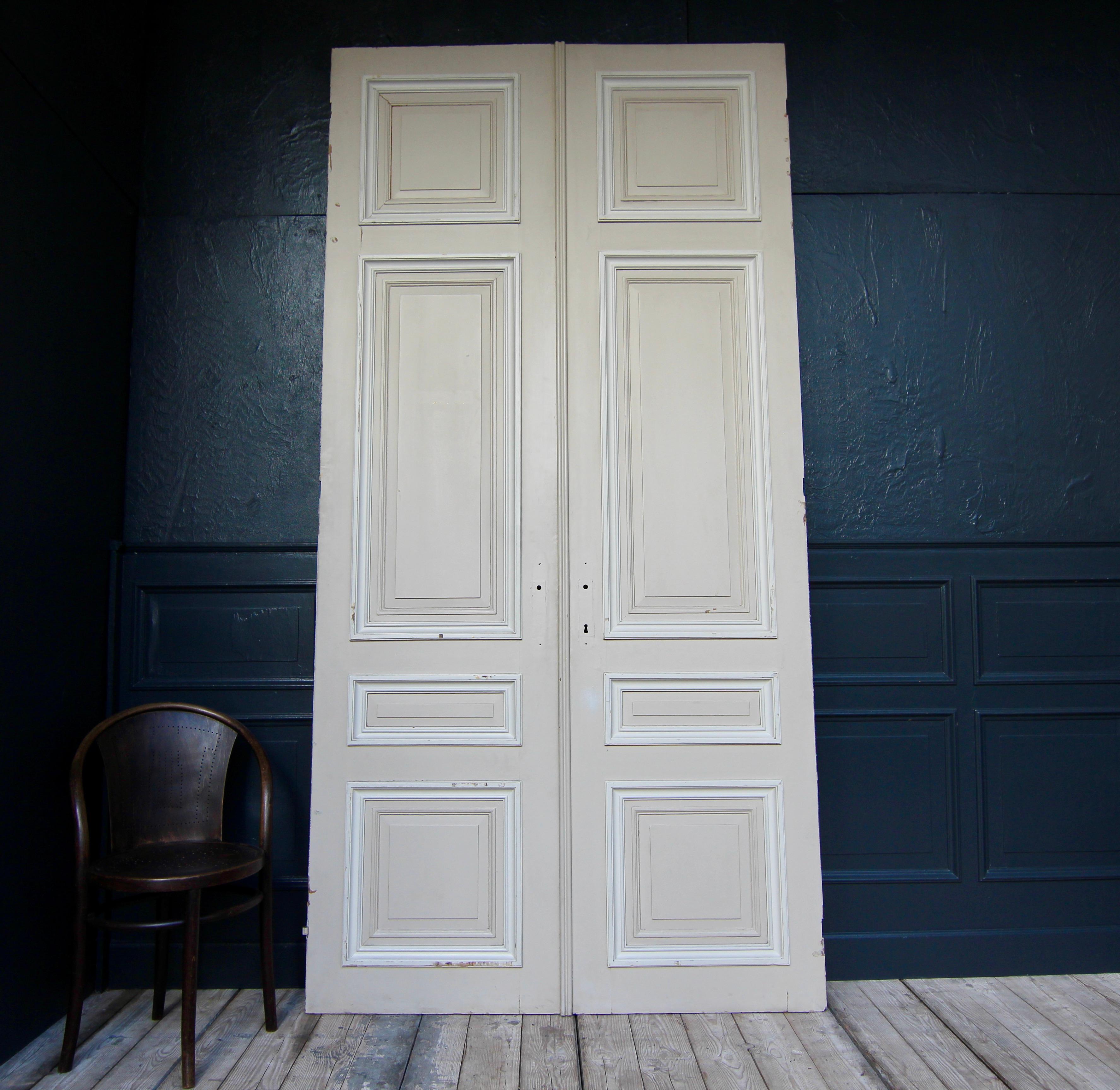 Tall French double door from the 1st half of the 20th century. Made of oak and painted. Unrestored condition.

Double door in frame construction with 4 coffered panels each.

One side in a cream colour, the other side in old brown.

Dimensions: 
285