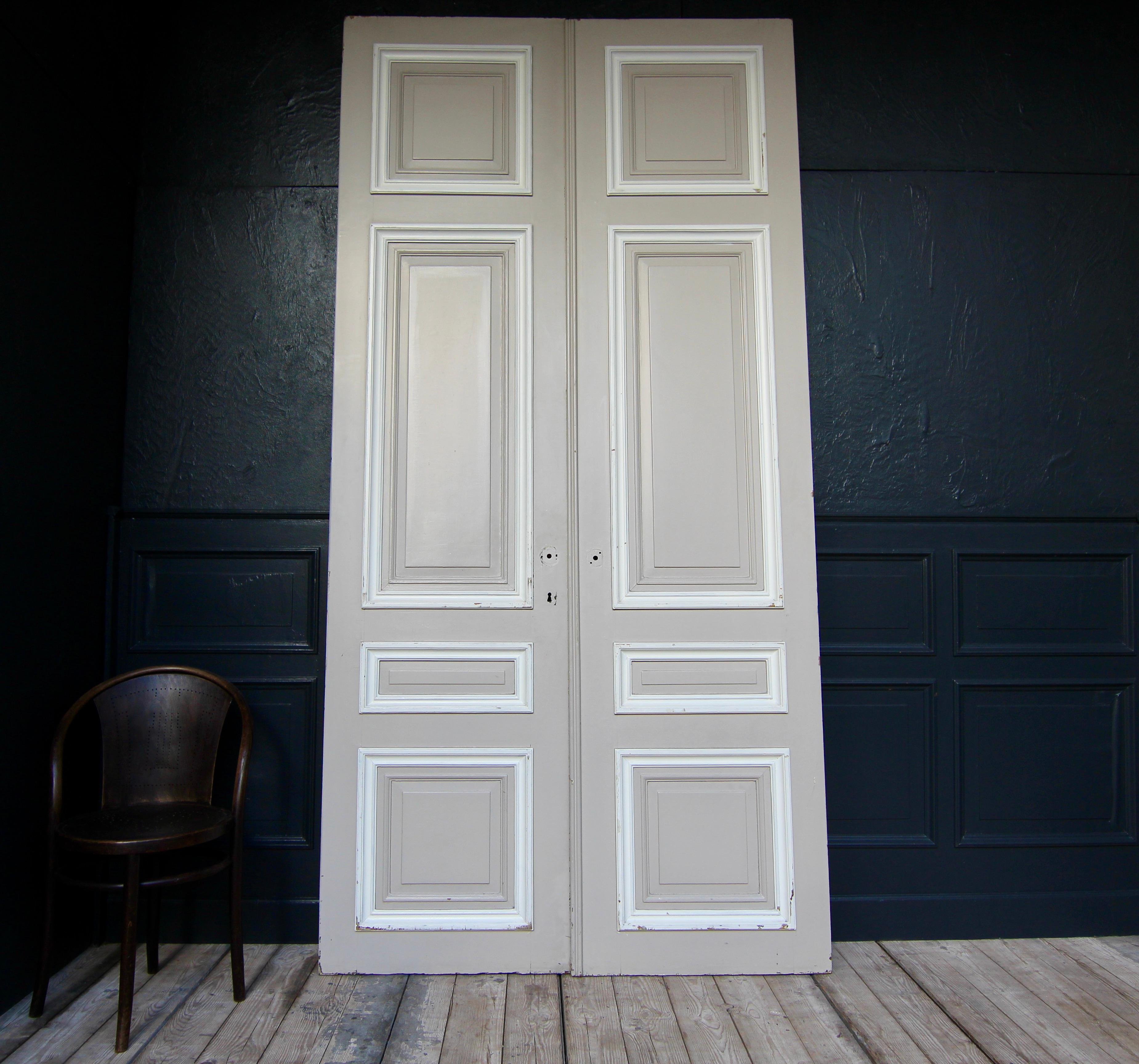 Tall French double door from the 1st half of the 20th century. Made of oak and painted. Unrestored condition.

Double door in frame construction with 4 coffered panels each.

Both sides in a taupe-like colour, each with white profiles, old