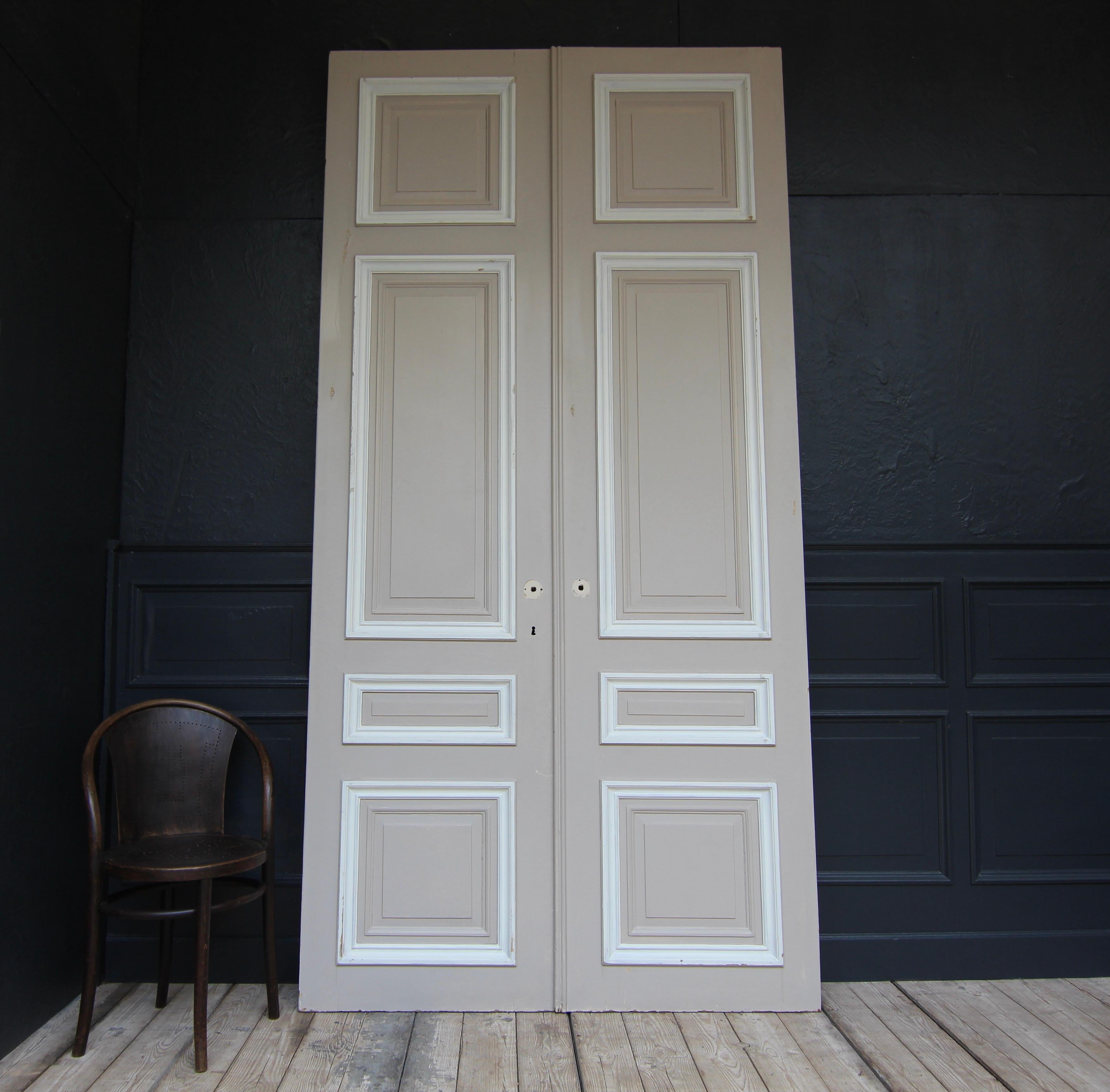 Tall French double door from the 1st half of the 20th century. Made of oak and painted. Unrestored condition.

Double door in frame construction with 4 coffered panels each.

One side in a taupe-like colour, the other side in a cream colour, each