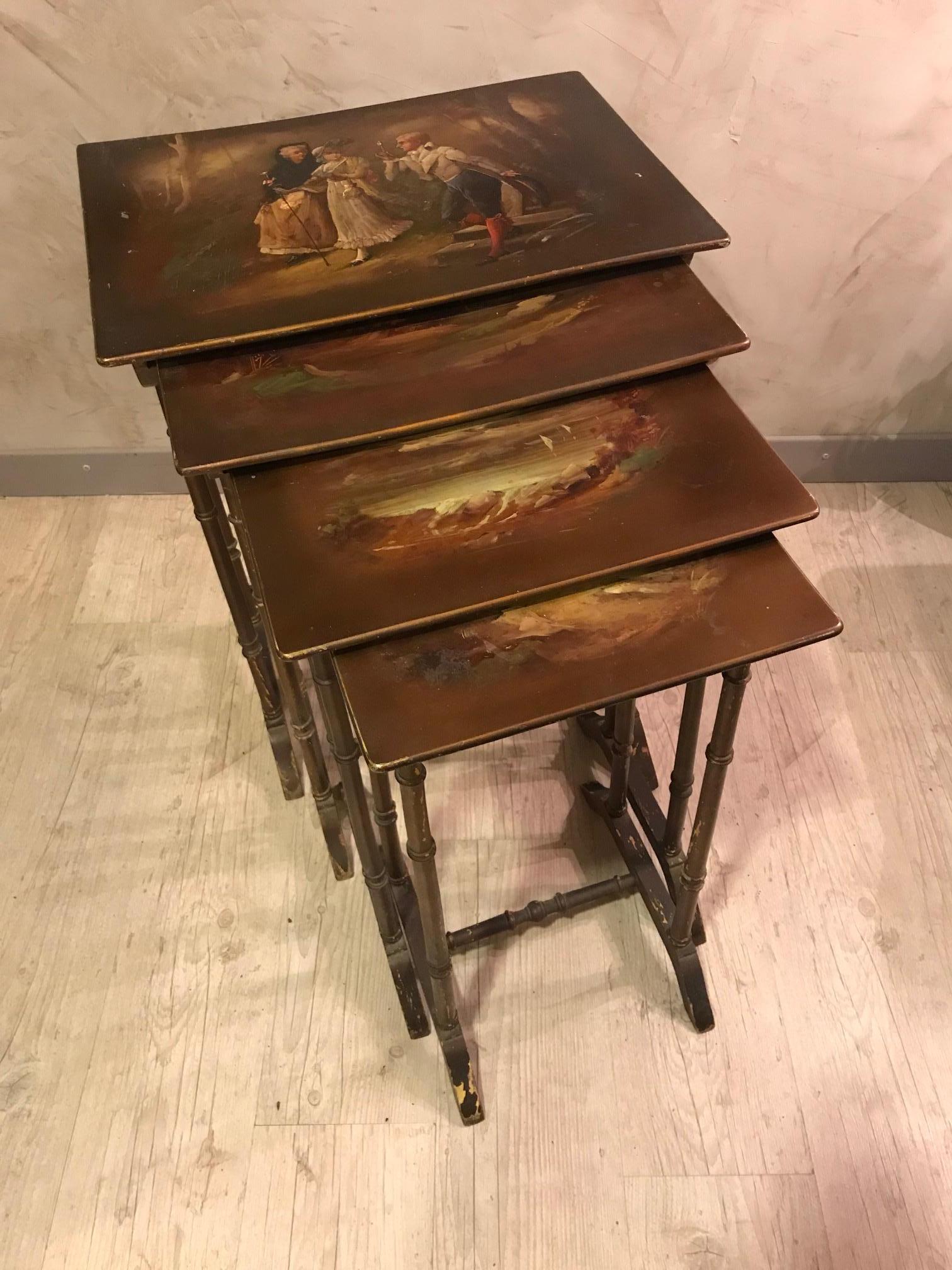 Très belles et originales tables gigognes en peinture française des années 1900. 
Quatre tables gigognes avec chacune une peinture différente, sur la plus grande on peut voir deux femmes marchant et un homme avec une loupe, scène très romantique.