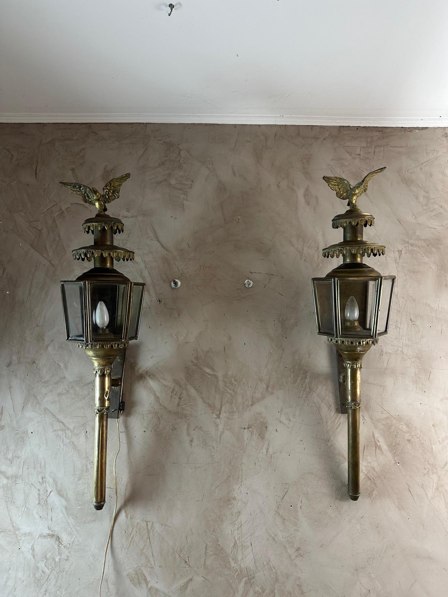 Beautiful and large pair of 19th century coachman's lanterns in brass and sheet metal.
Hexagonal shape in glass and brass. Topped with an eagle with outstretched wings in Empire style bronze. Electrically mounted. Small door at the back to access