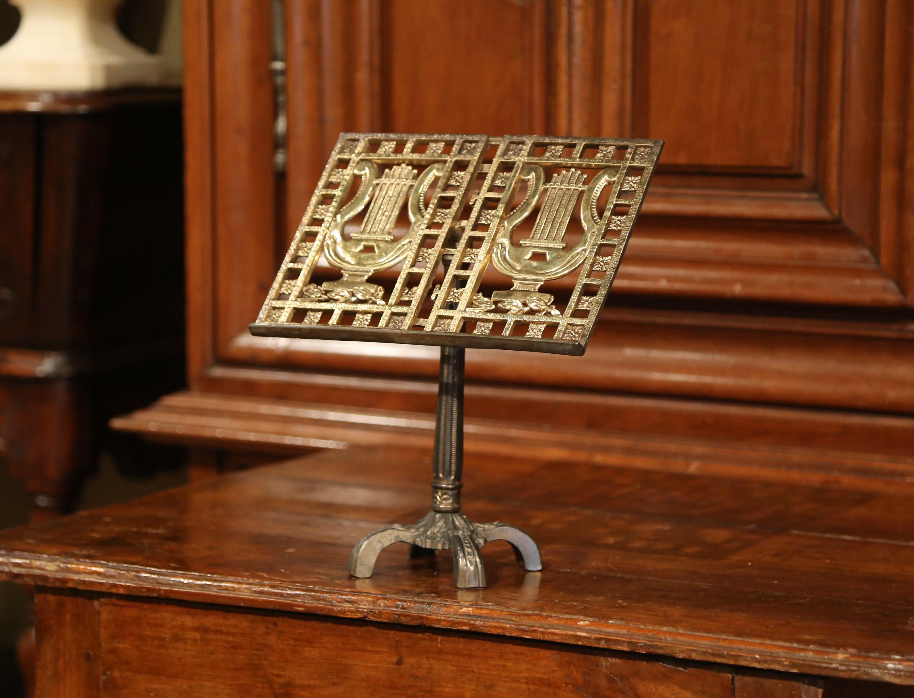 Display your music score on this decorative, antique stand! Crafted in France, circa 1920, the music stand has a patinated brass base and features an intricate design with a lyre and floral decor. The table recipe book stand is in excellent