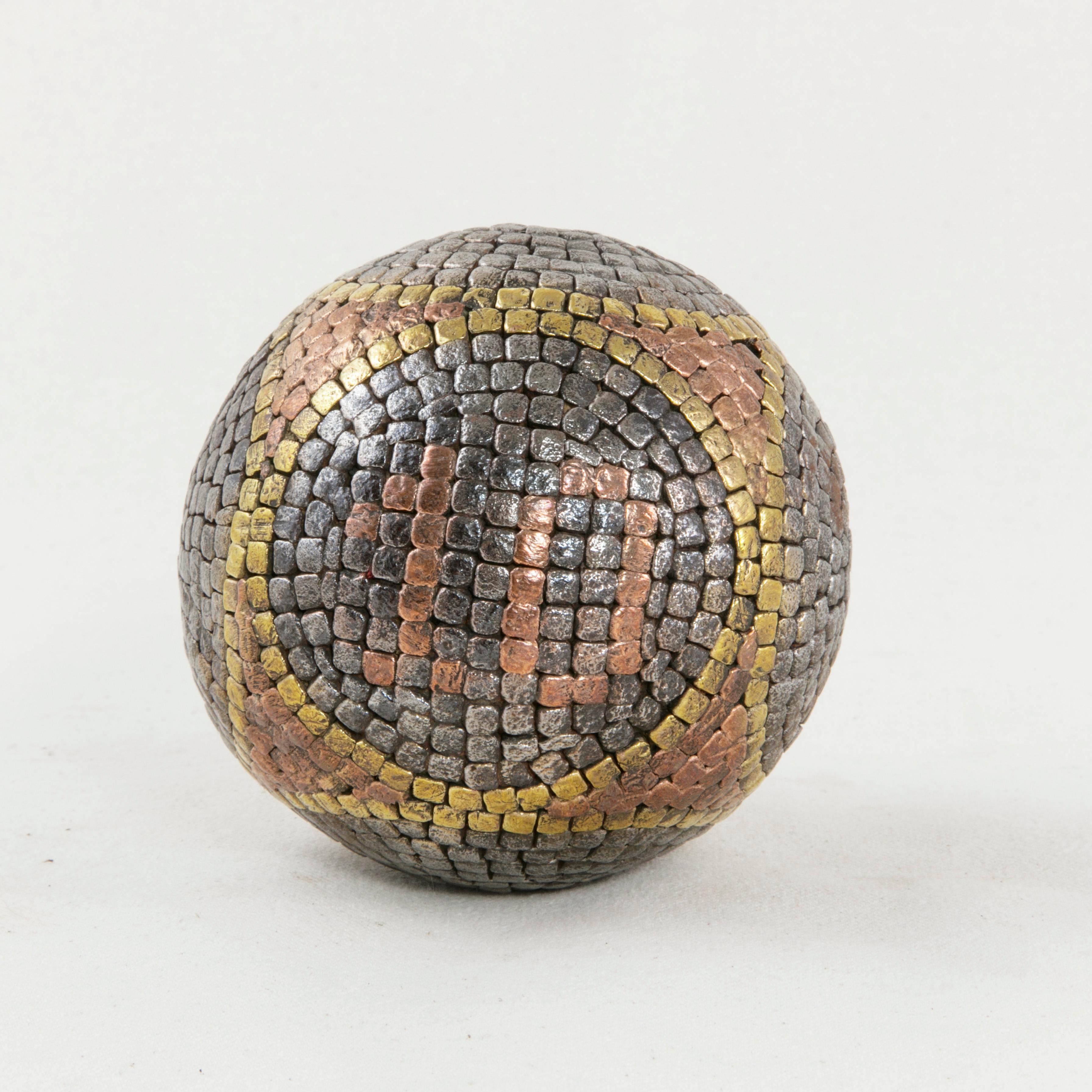 This French artisan-made petanque ball from the early twentieth century features copper, brass, and steel stud nails that form six circles around its wooden core. In one of the circles are copper studs that form the number 10. Petanque is a lawn