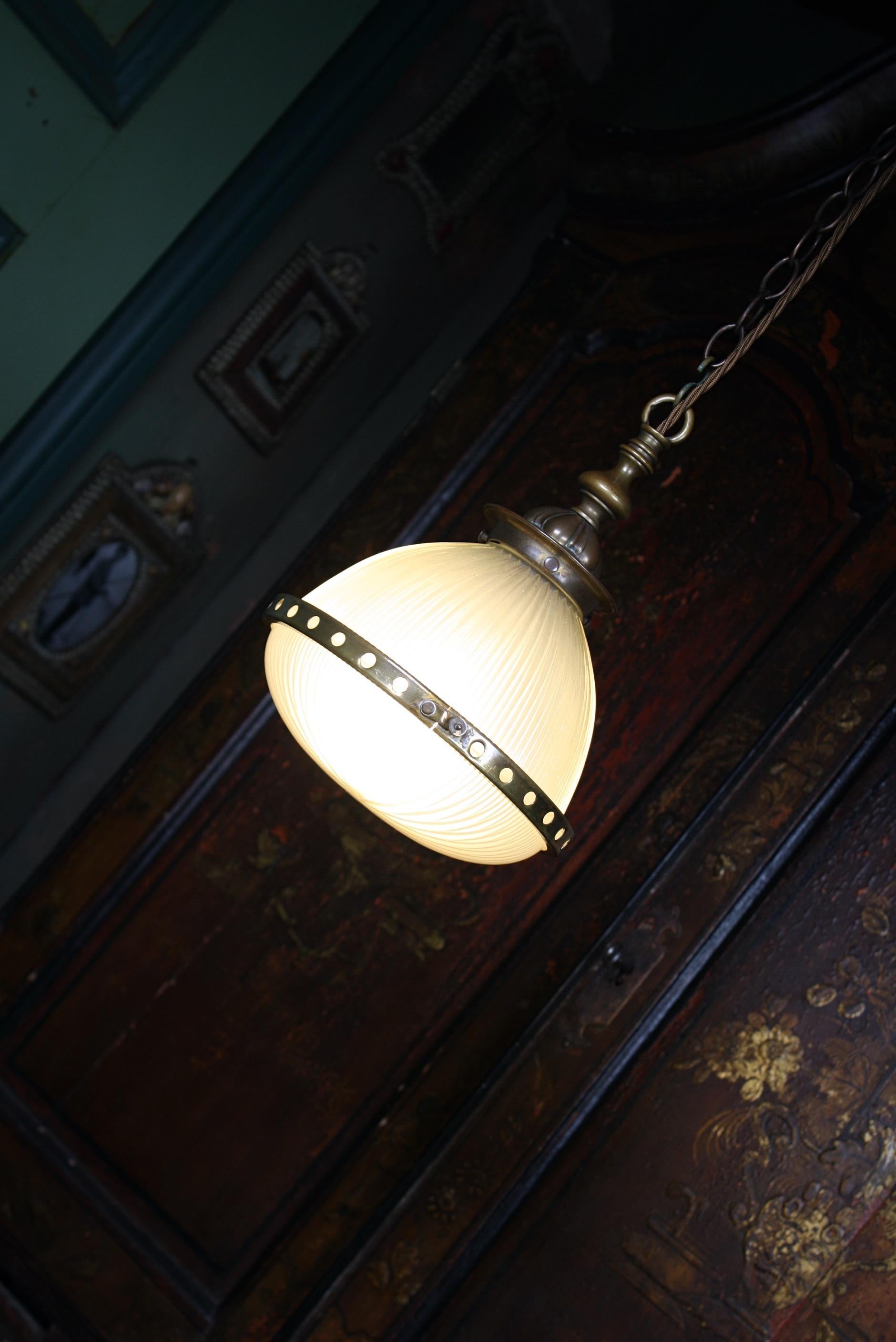 A diminutive two part Holophane lantern, with pierced brass central band and heavy gauge cast brass gallery.

All metal section have age related oxidization, glass in perfect condition.

The light comes with its original brass chain, a new cast