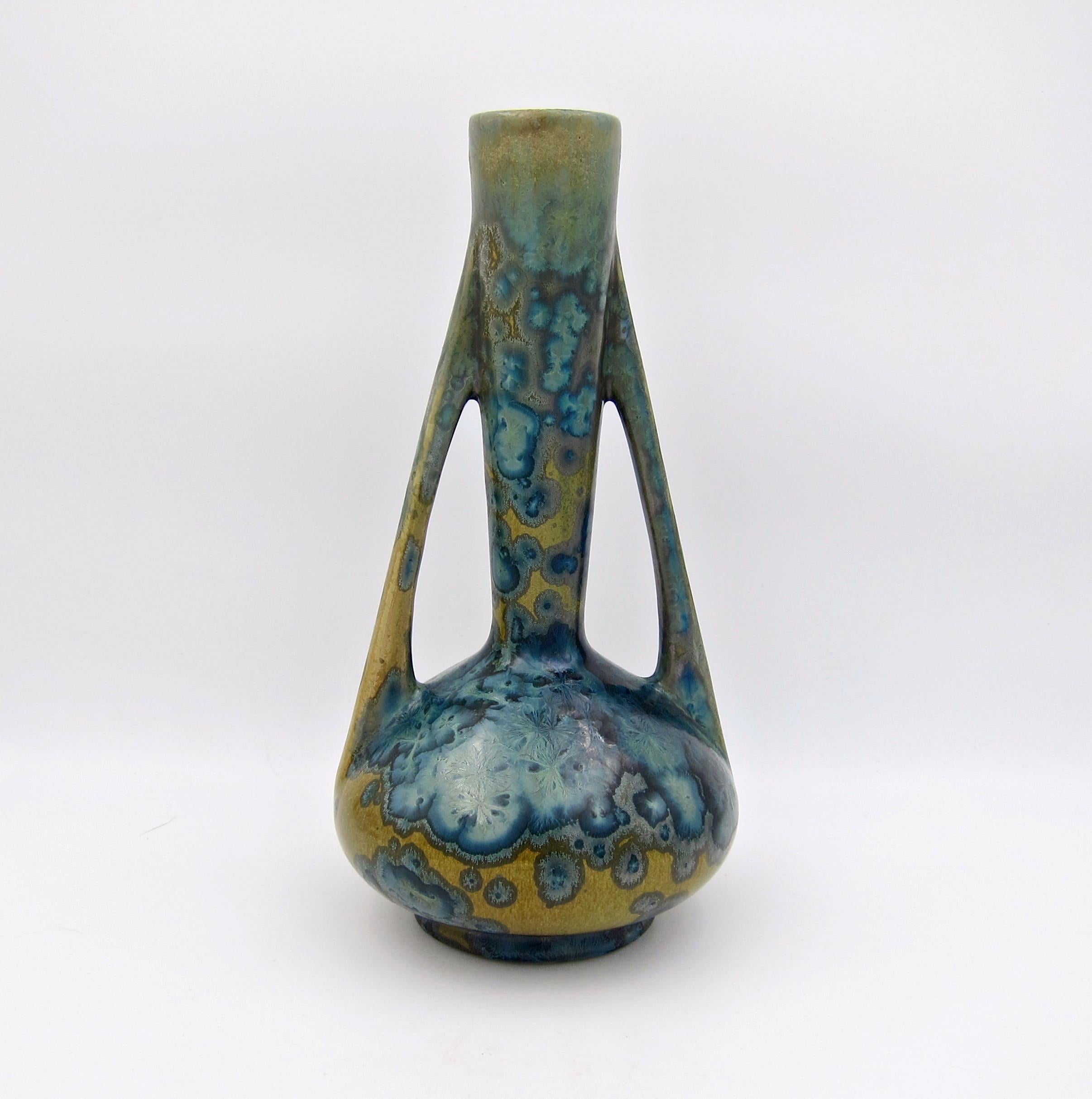 Un superbe vase en poterie d'art Art Nouveau du tournant du 20ème siècle de la poterie de Pierrefonds de France. Ce récipient antique à deux anses date d'environ 1905 et est décoré d'une glaçure aux nuances de bleu variées sur un fond beige/écossais